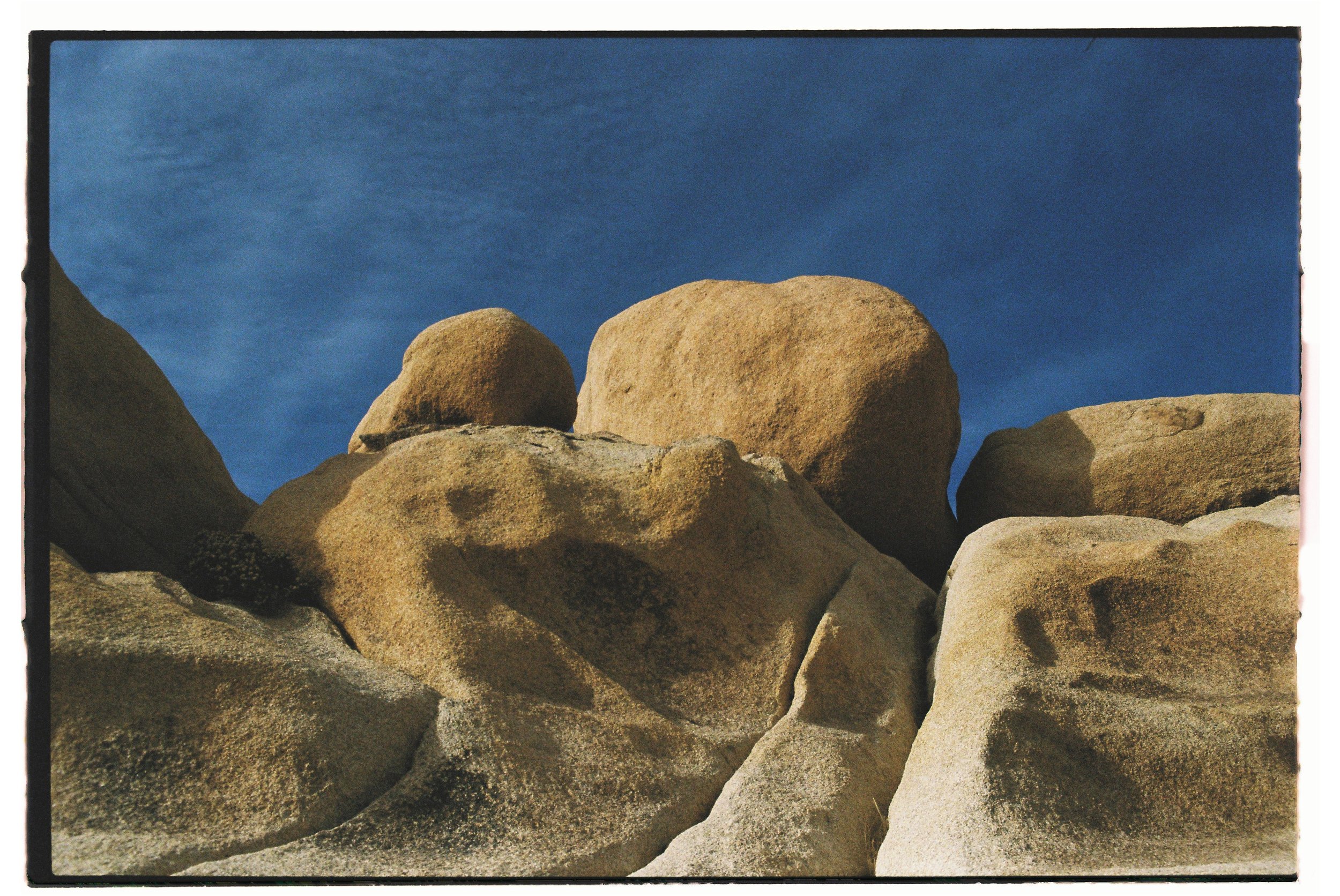 A group of large, weathered rocks stacked against a blue sky.