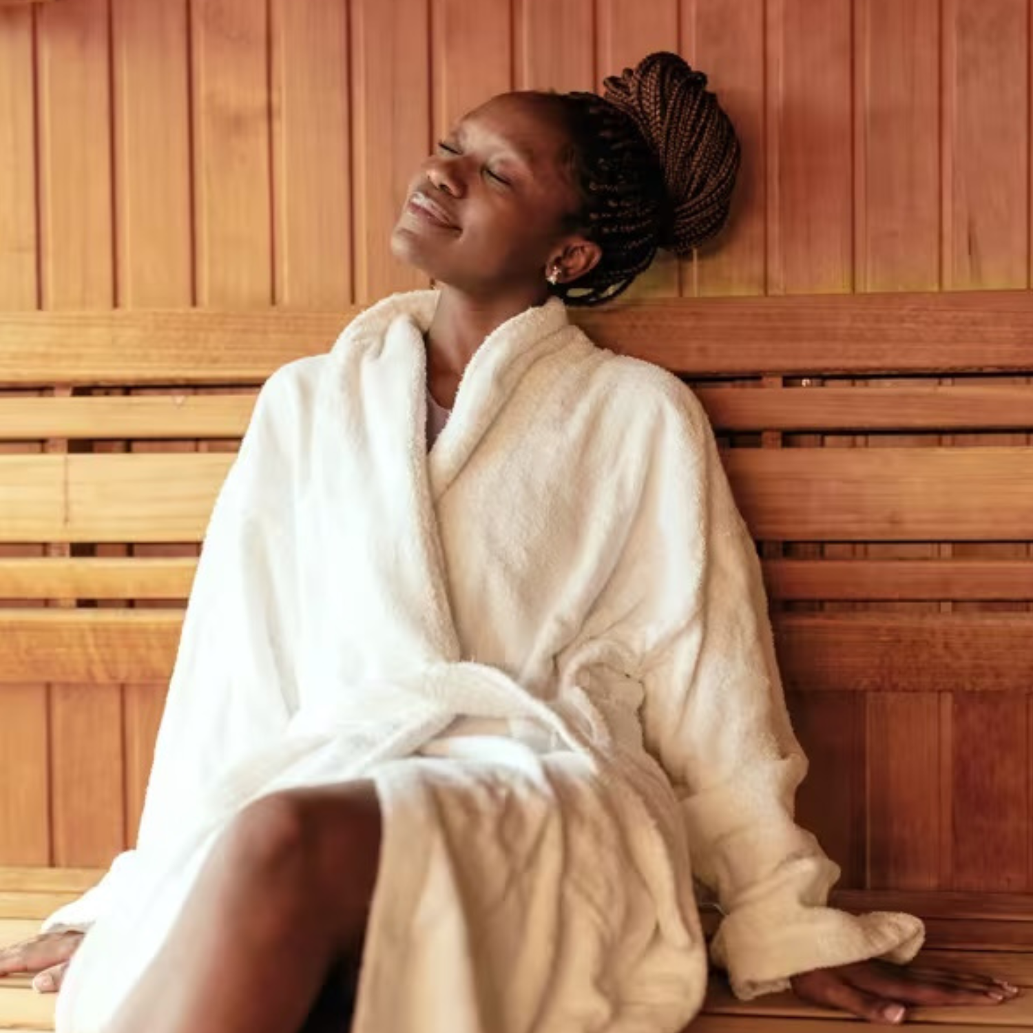 Woman wearing a bathrobe sitting in a sauna smiling