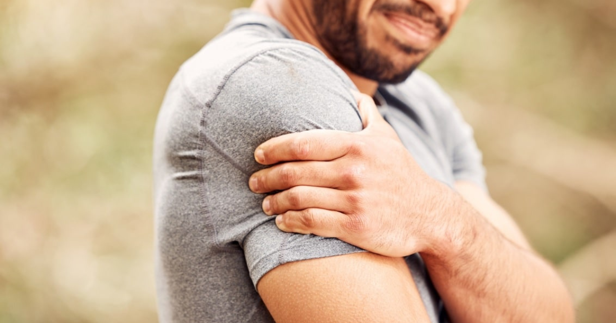 Man in gray shirt massaging arm and shoulder