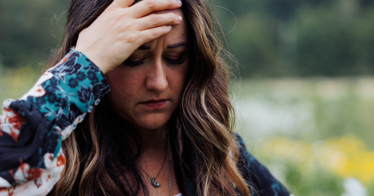 Woman in distress holding her hand up to her forehead