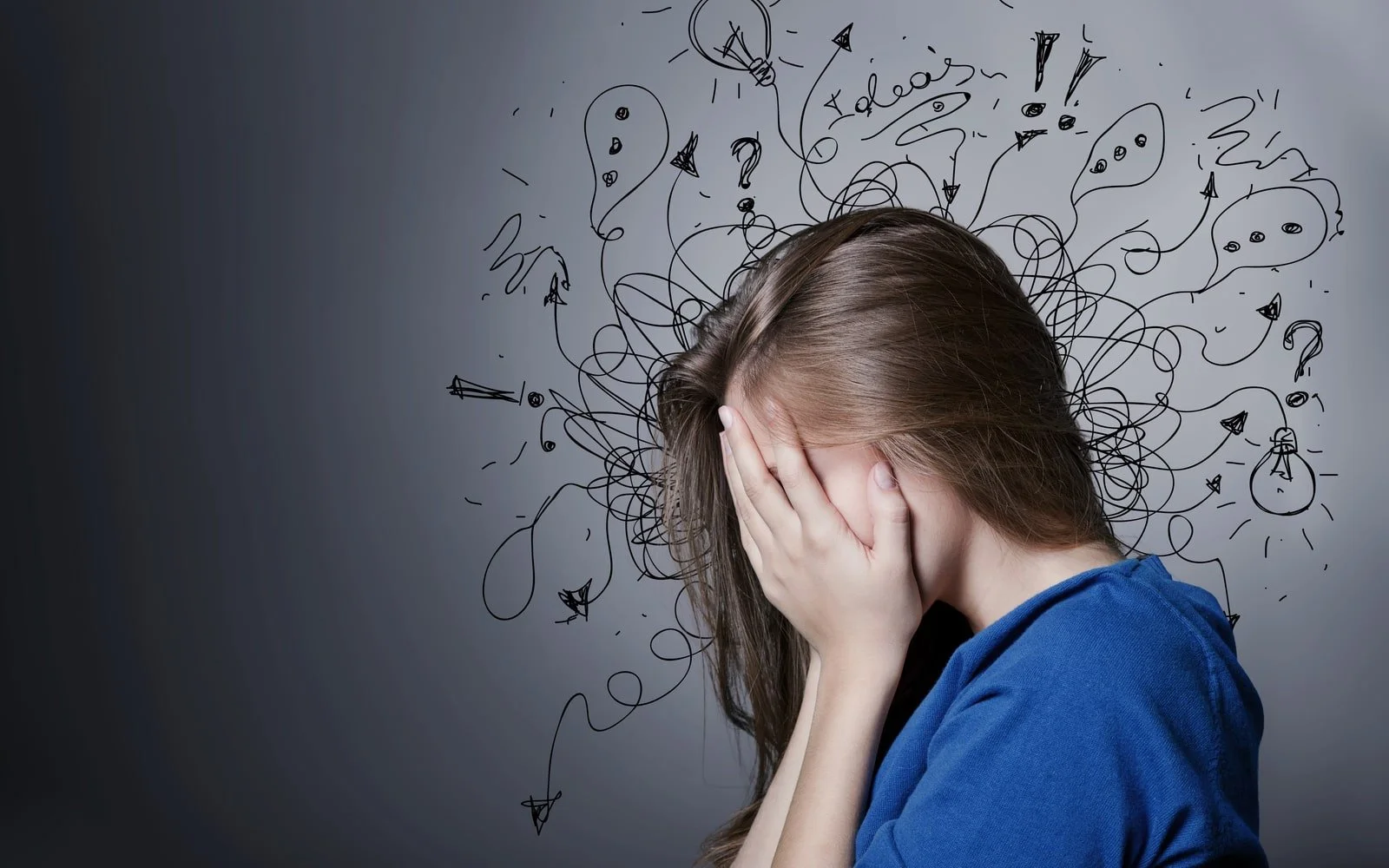 Young woman wearing a blue shirt holding her face in her hands
