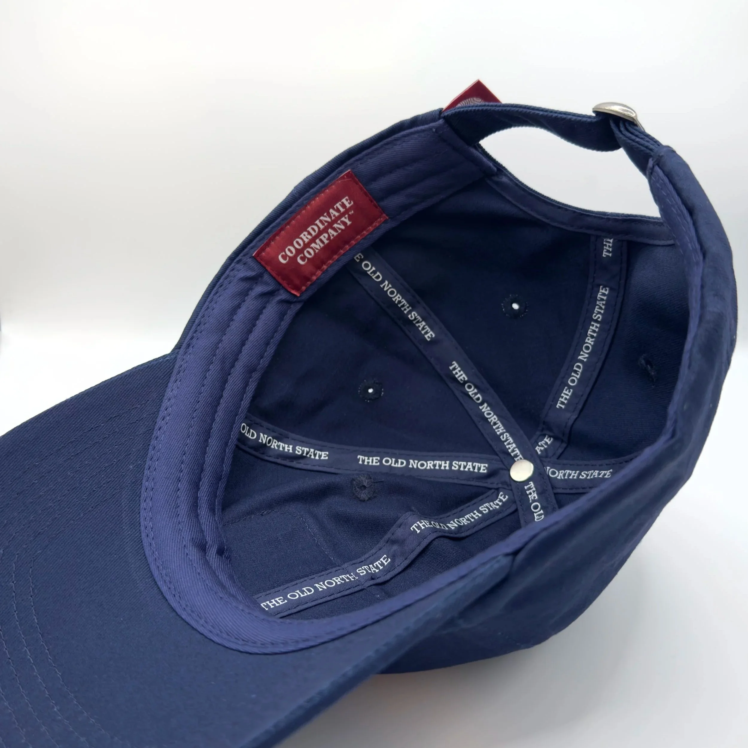 Inside of navy dad hat showing “The Old North State” inner taping and red Coordinate Company label