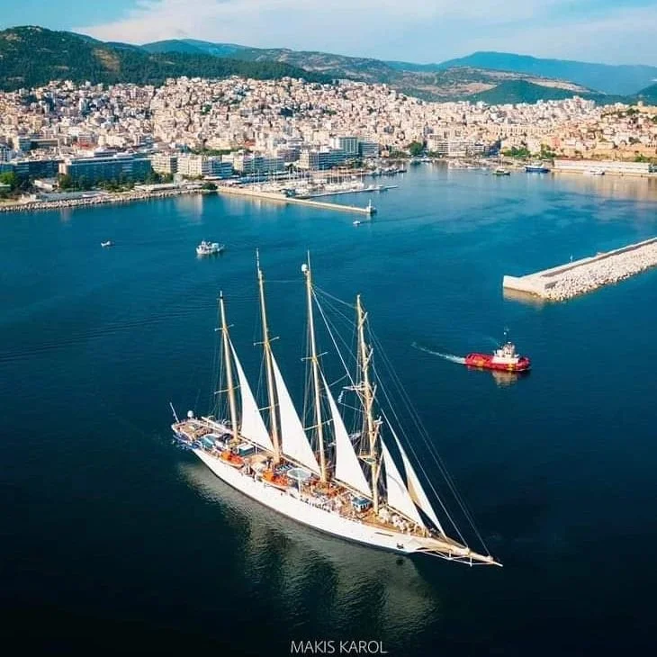 Tall ship sailing into Kavala harbour with the city behind