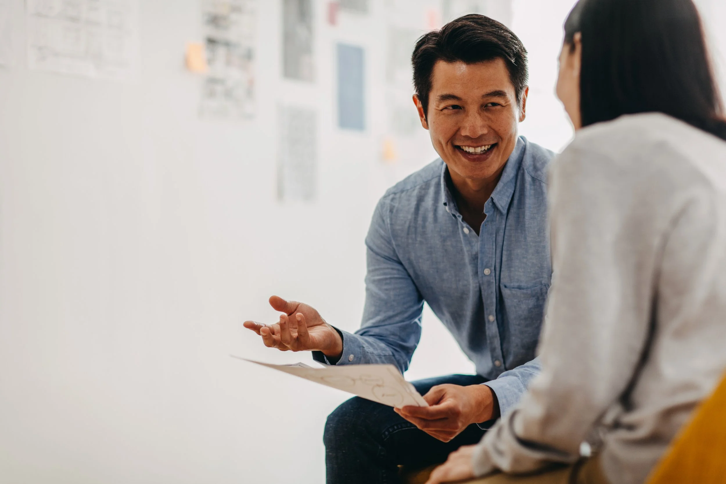 Two coworkers discussing ideas while reviewing documents during a meeting