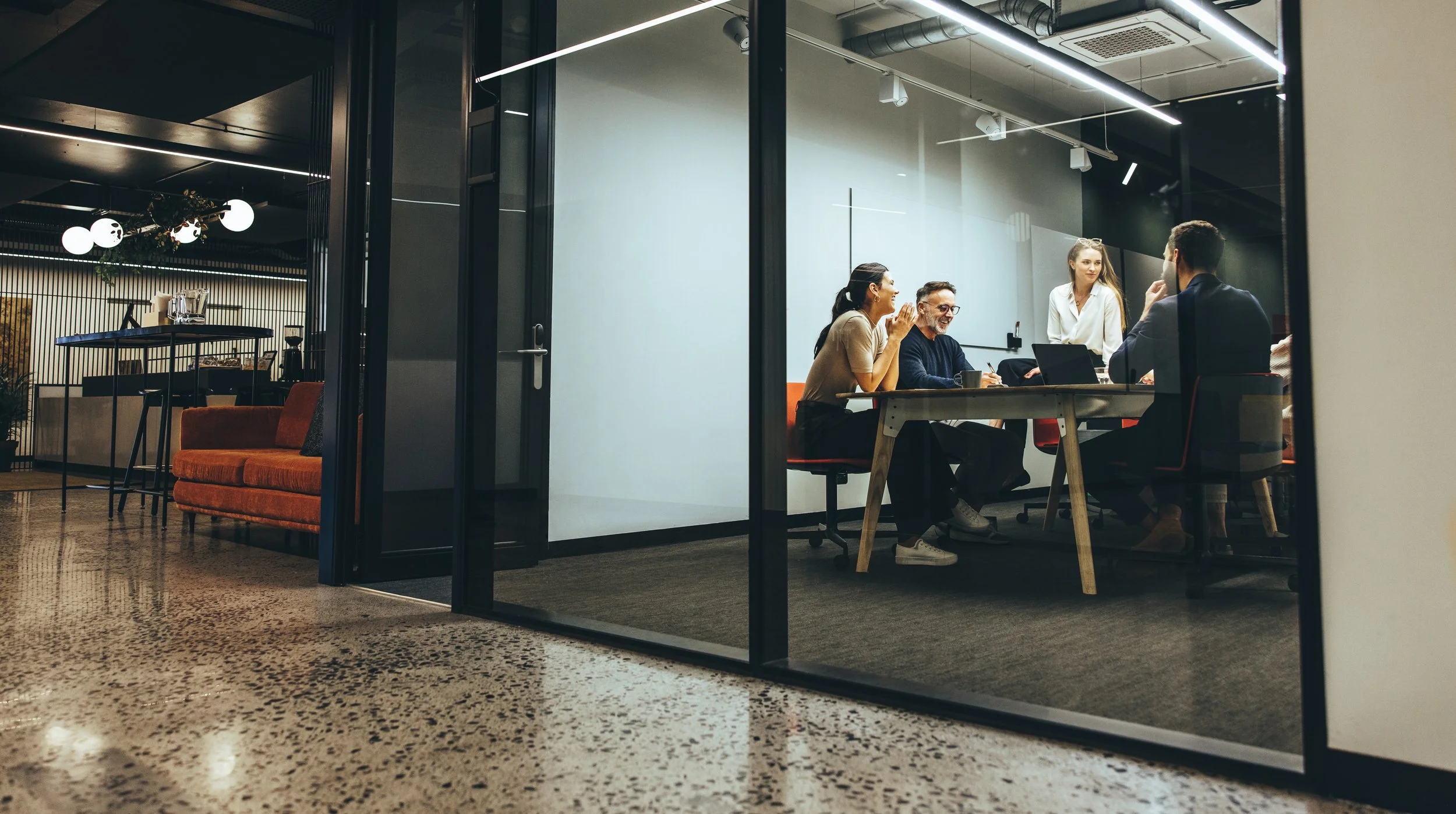 Colleagues holding a meeting around a table in a glass-walled conference room