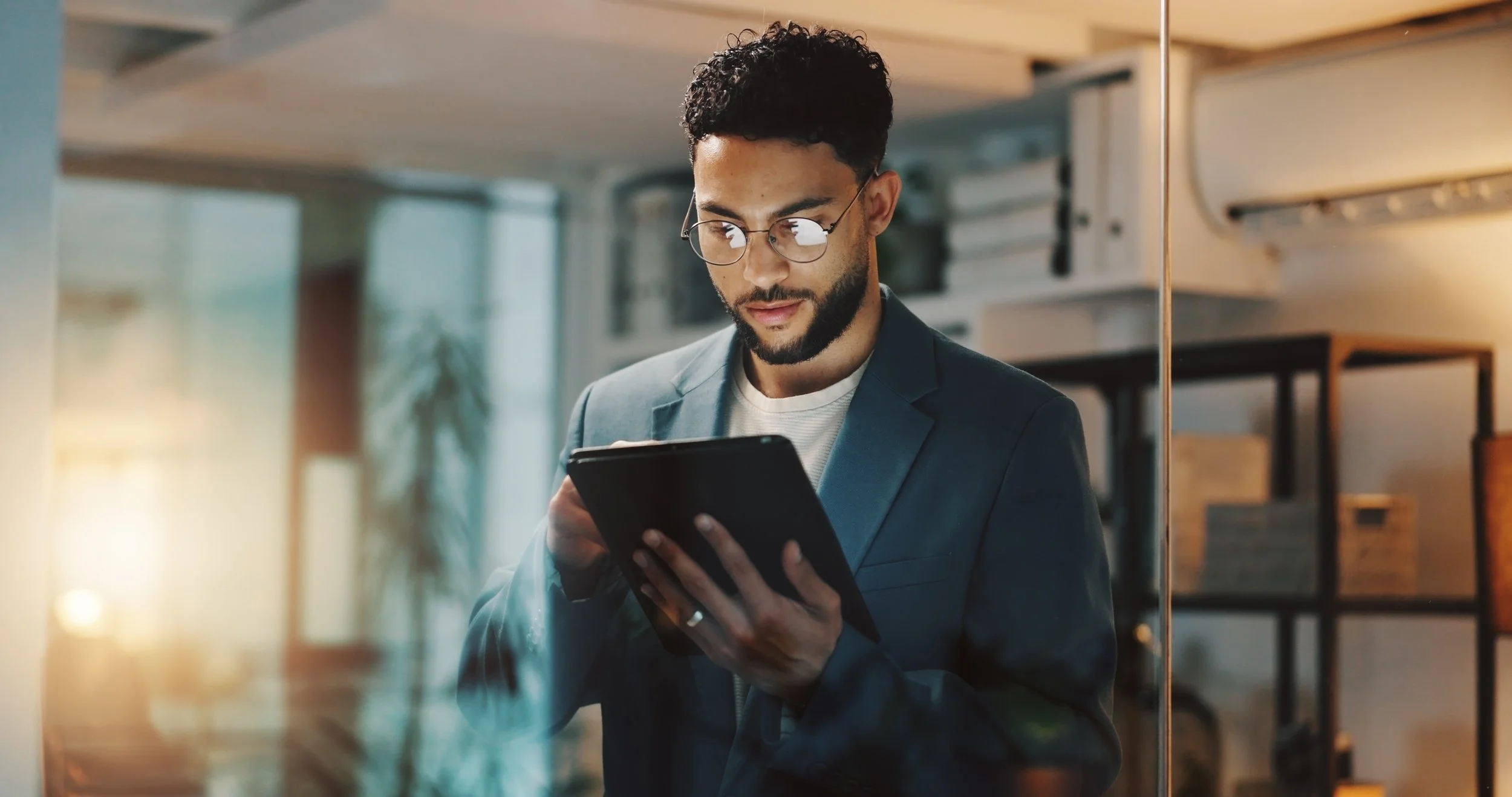 A man looking at a digital tablet in a glass office