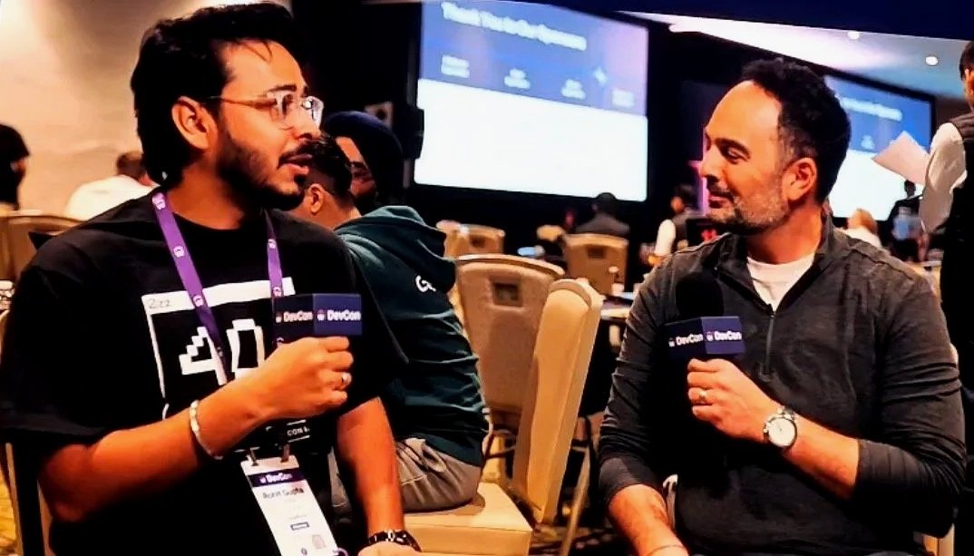 Two attendees at Workday DevCon 2026 in conversation, holding DevCon-branded microphones in a conference room setting