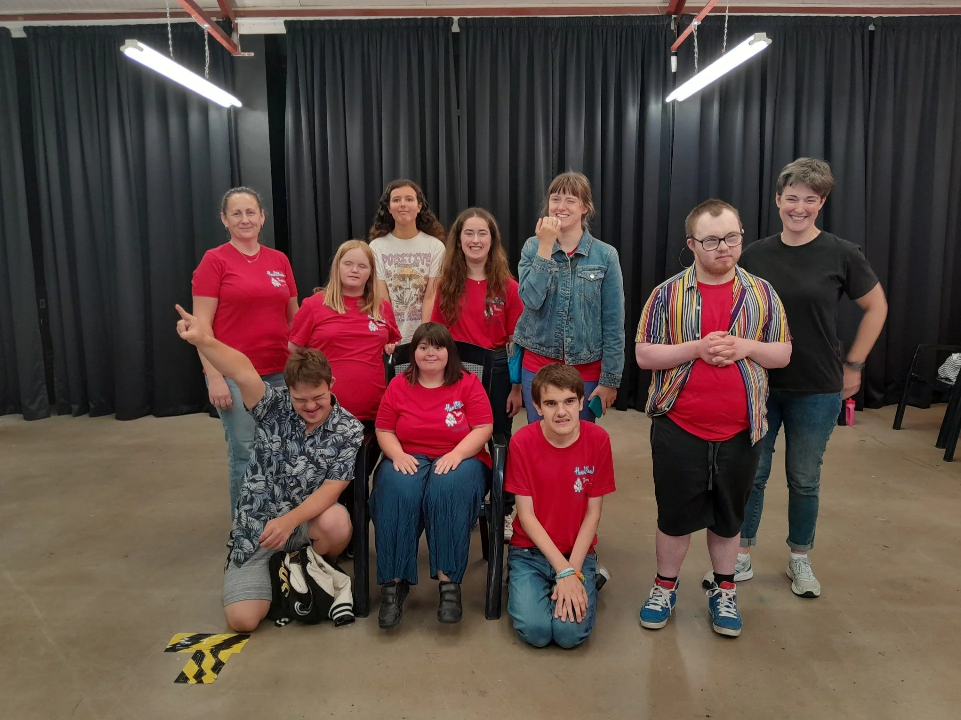 A photo of a group of participants from a perfomance session with the charity Head2Head - 10 people grouped together smiling there is a girl in a wheelchair