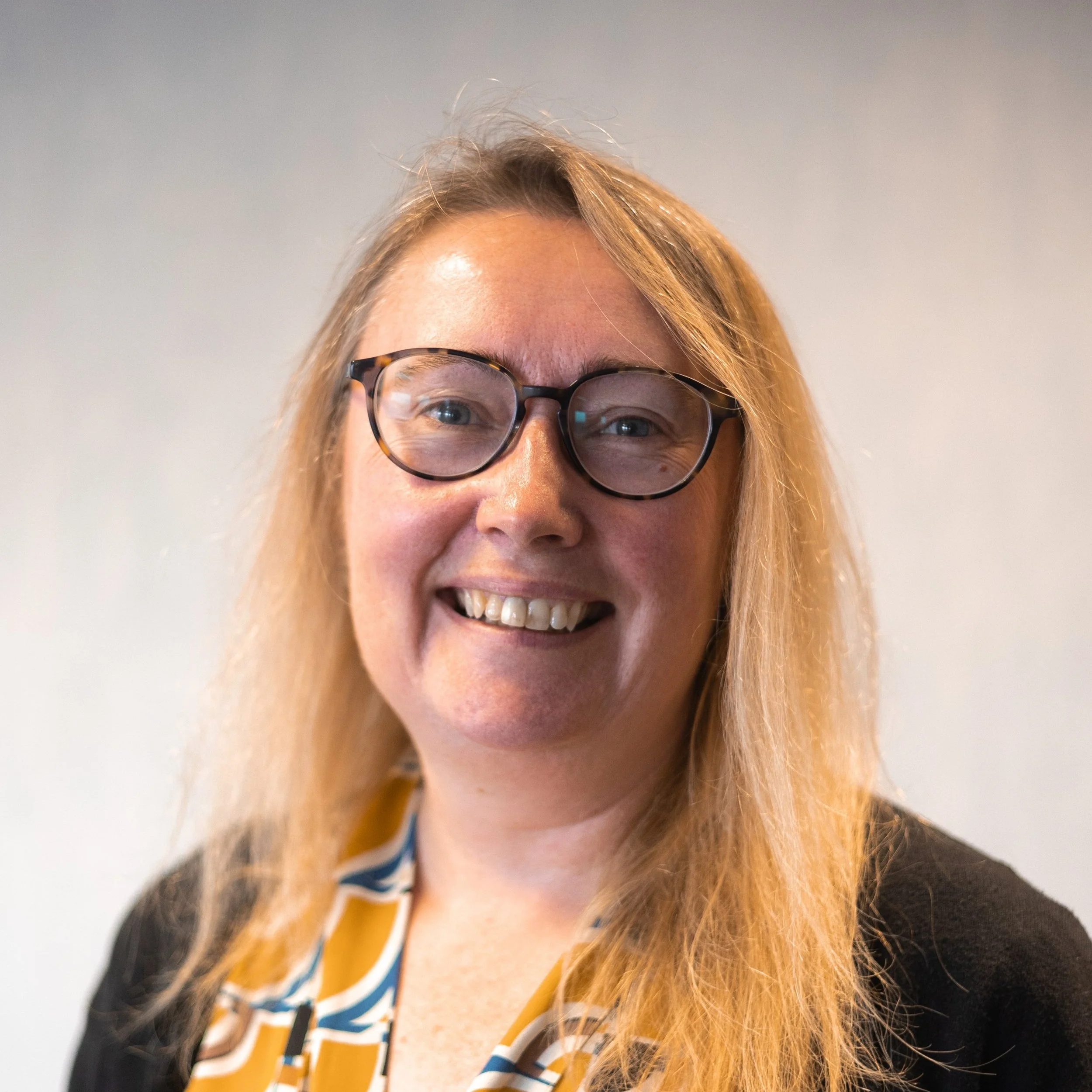 Tamalie Newbery smiles wearing dark rimmed glasses