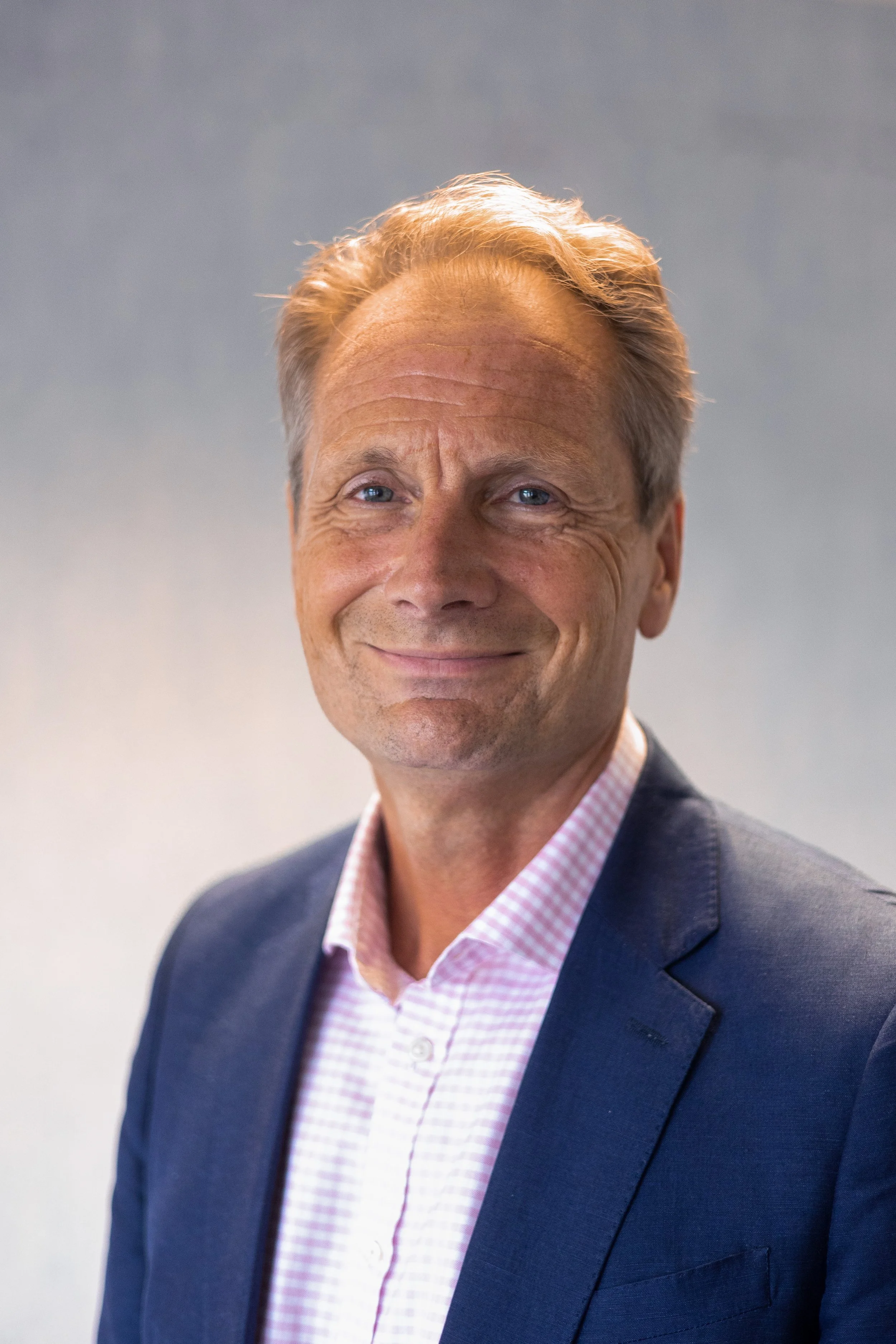 David Stead in a blue suit with open shirt, he is smiling with short fair hair and is a white man