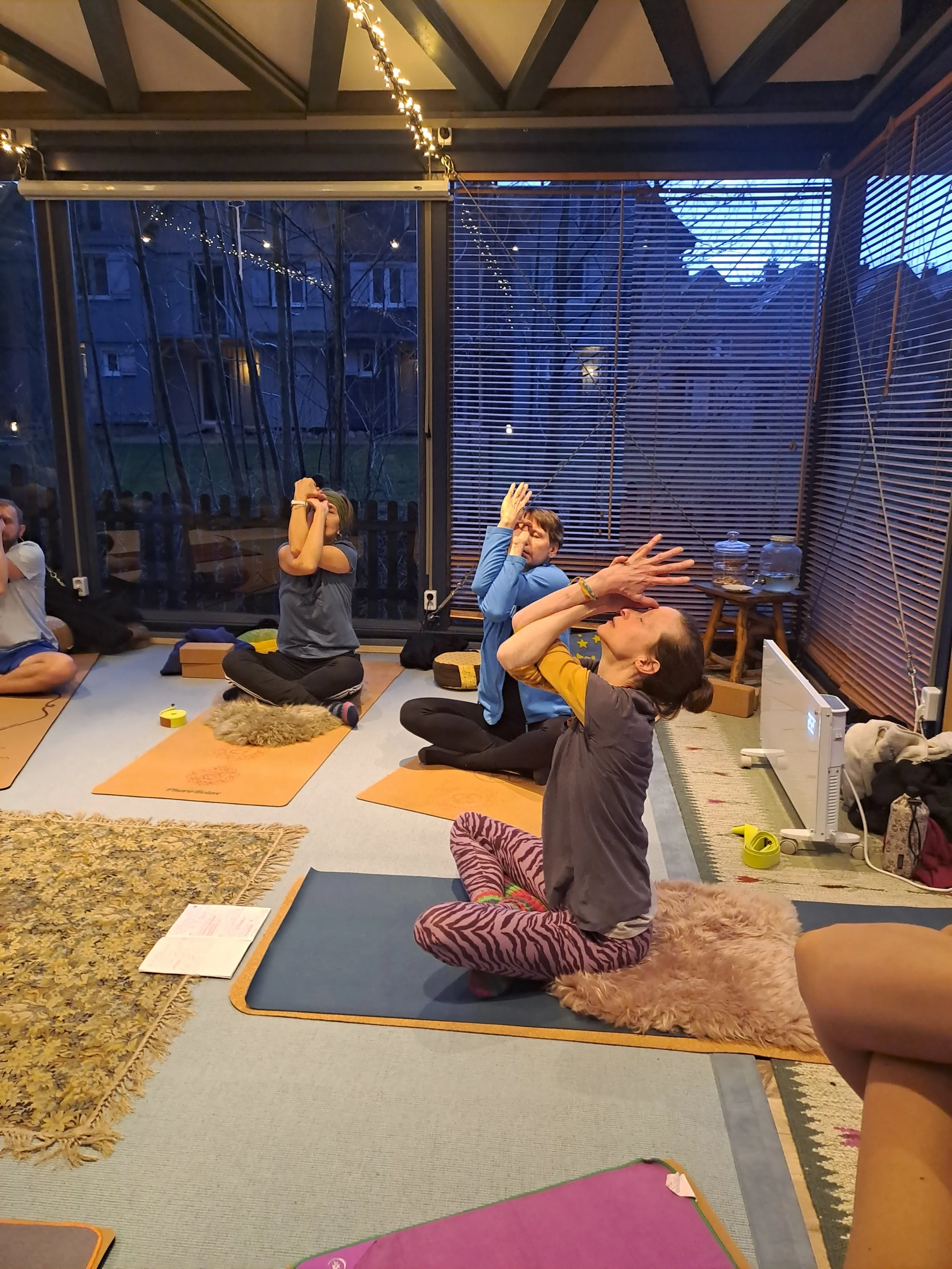 kleine Gruppe auf Yogamatten in Rückbeuge im gekreuzten Sitz mit Adlerarmen (Aufwärmung)