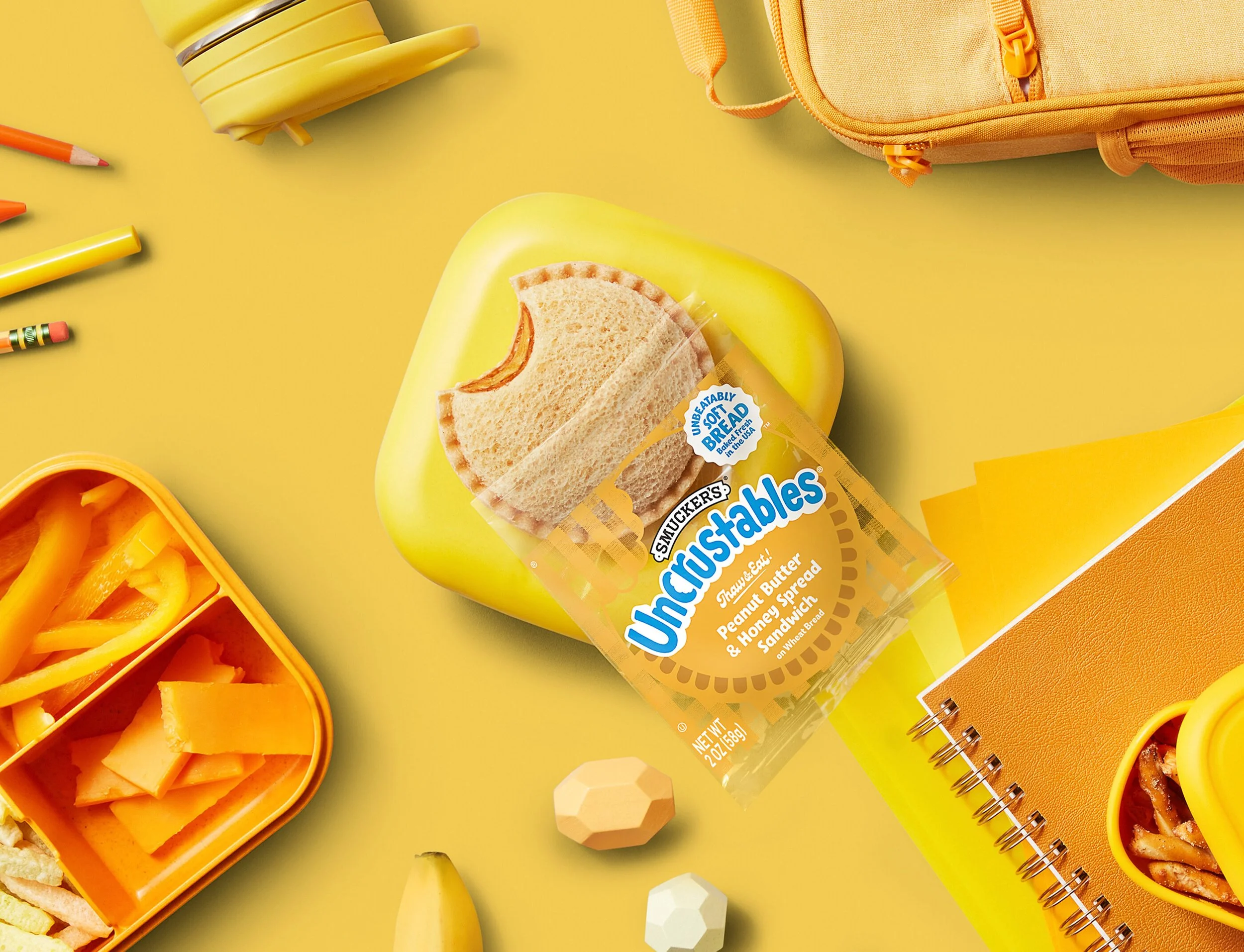 photo shows a peanut butter and honey sandwich atop a yellow background with other yellow snacks and toys.