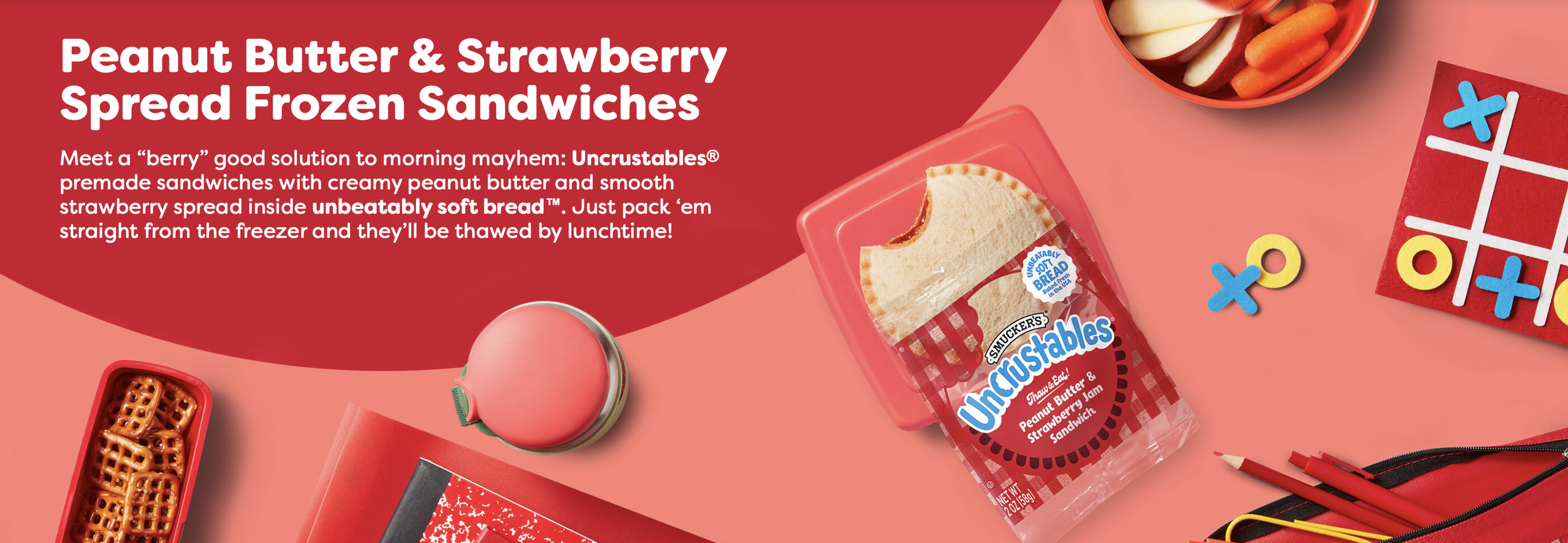 photo shows a peanut butter and strawberry uncrustable sandwich alongside a tin of pretzels, a tic-tac toe board, and other snacks.