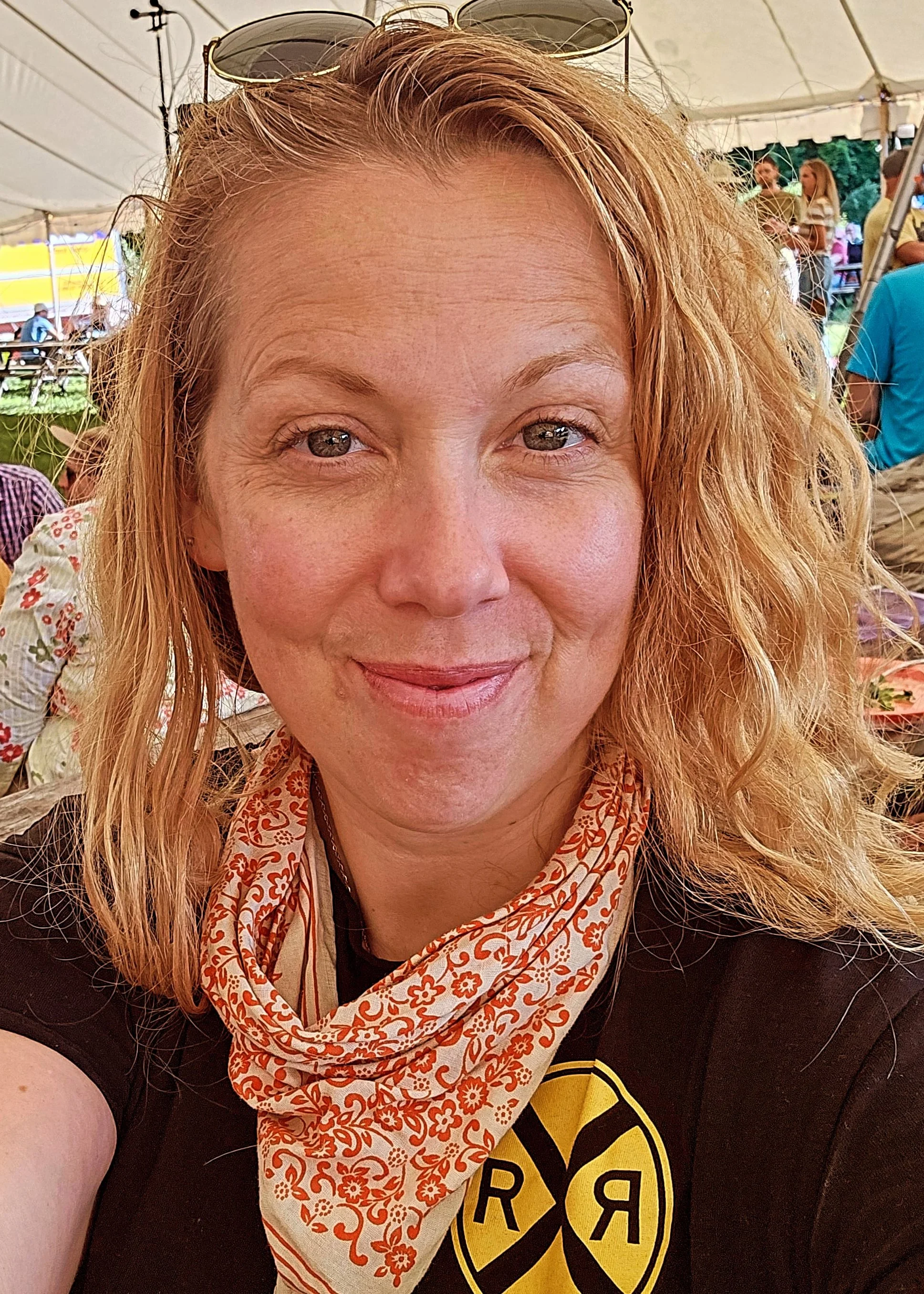 Colour portrait of a woman with long curly blonde hair, smiling.