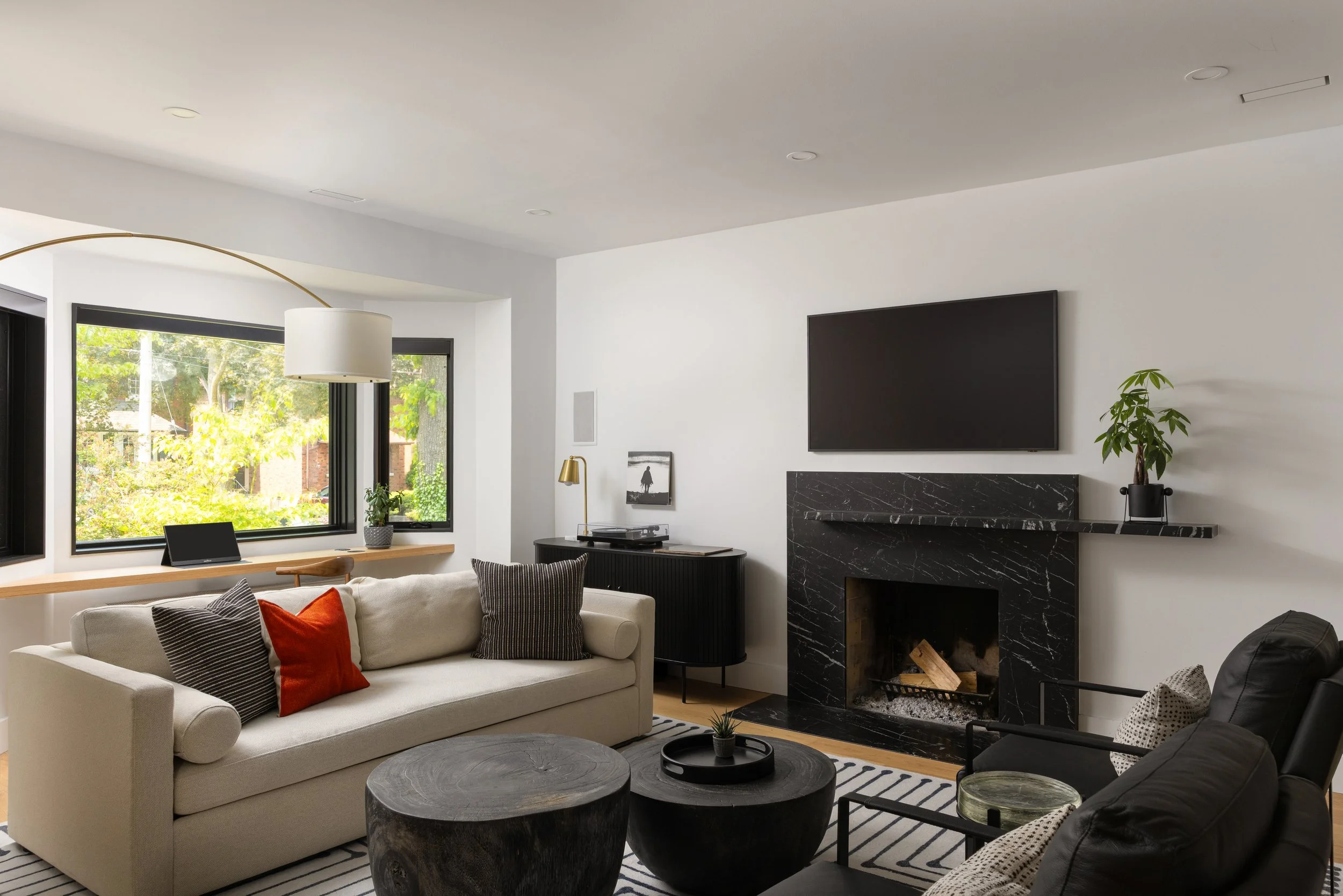 A bright, modern lving room featuring large windows and a black marble fireplace