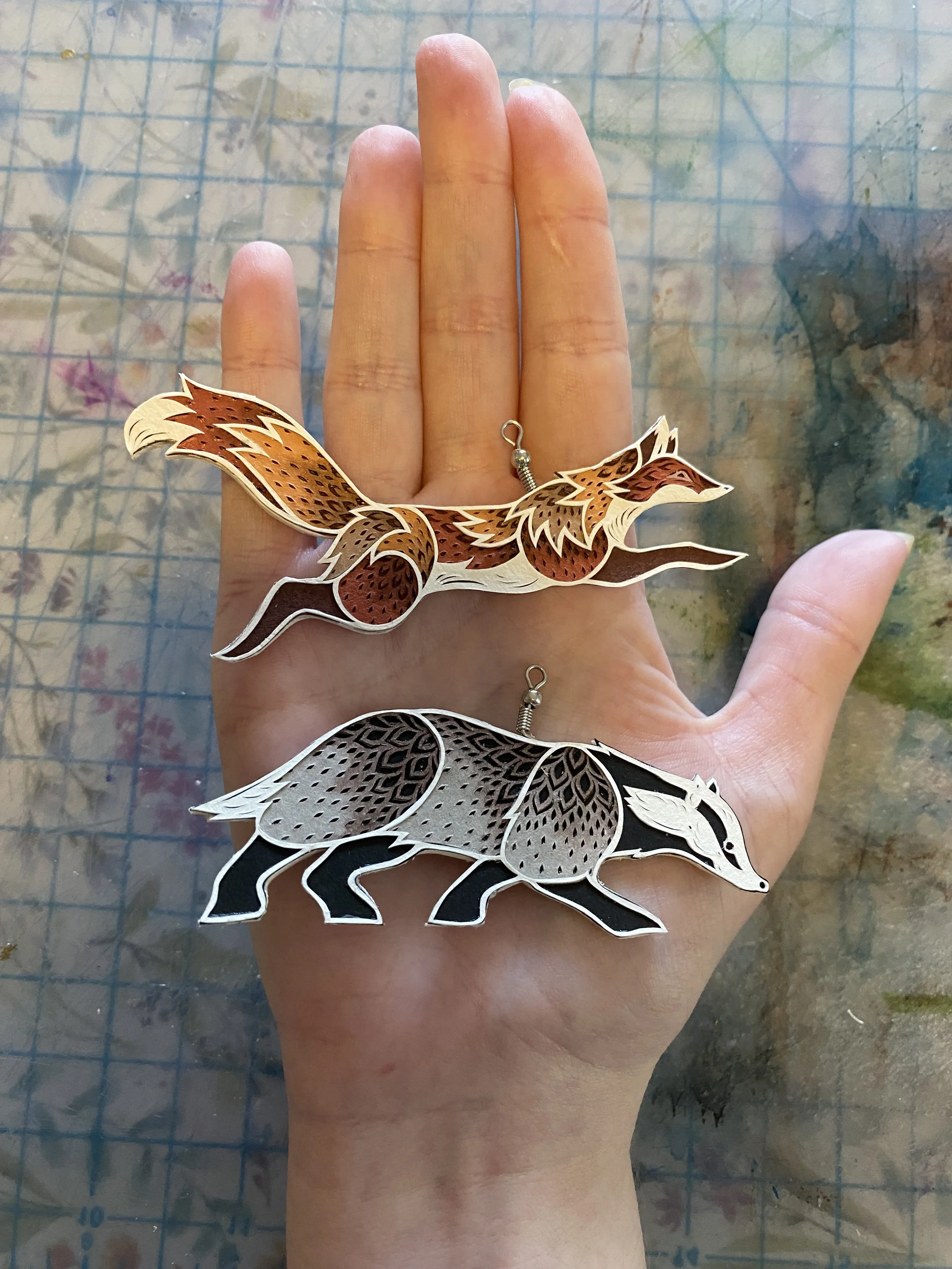 hand cut paper fox and badger ornaments. 2025 Holiday Collection