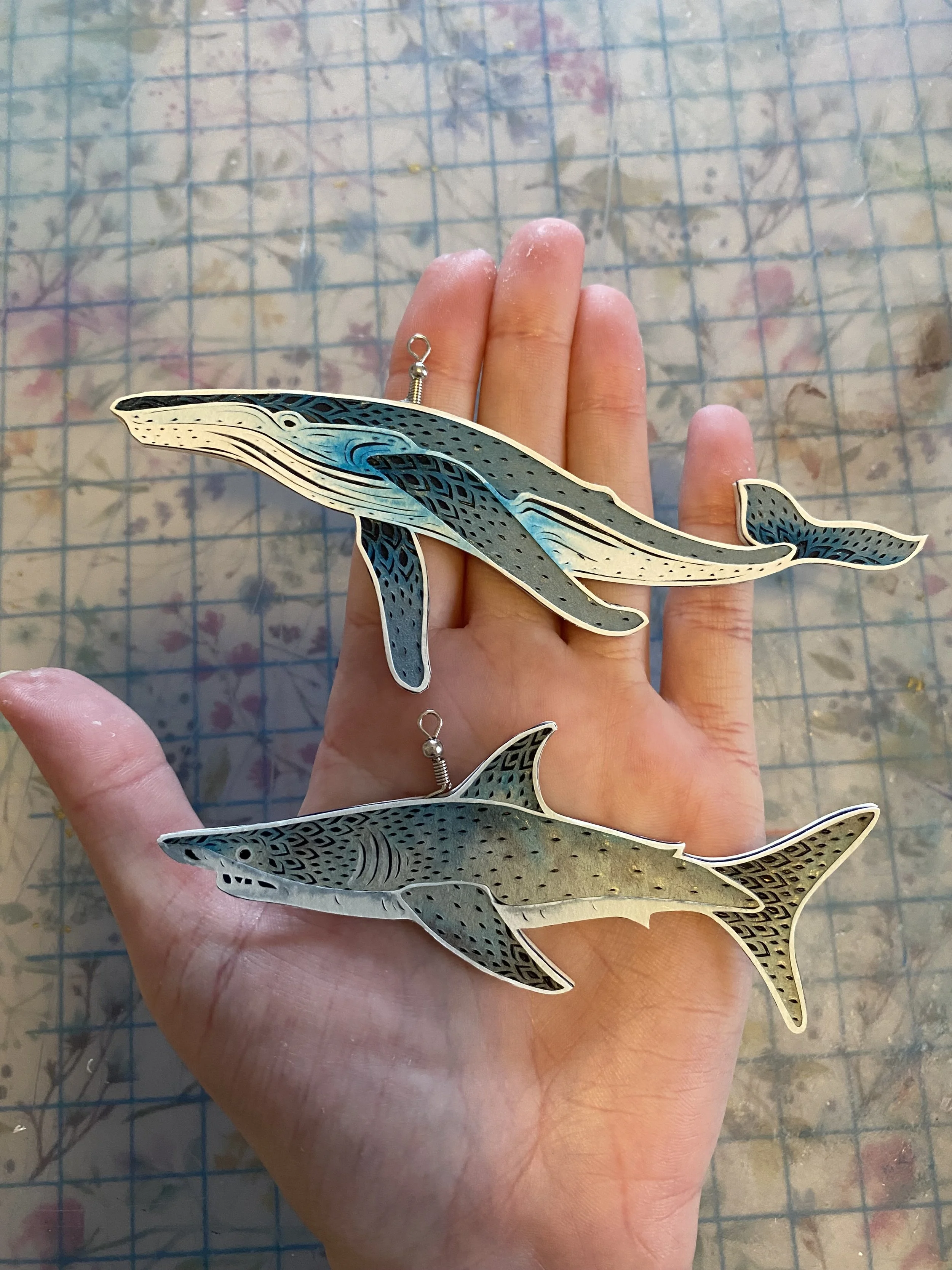 Hand cut paper blue whale and great white ornaments. 2025 Holiday Collection