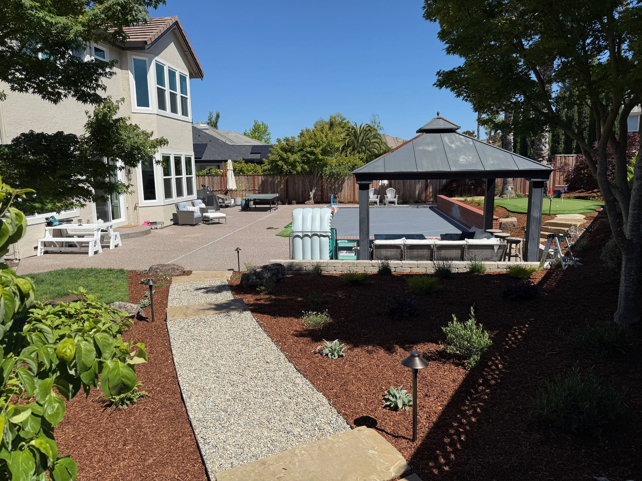 Gravel walkway in Petaluma backyard with surrounding landscaping and concrete patio. 