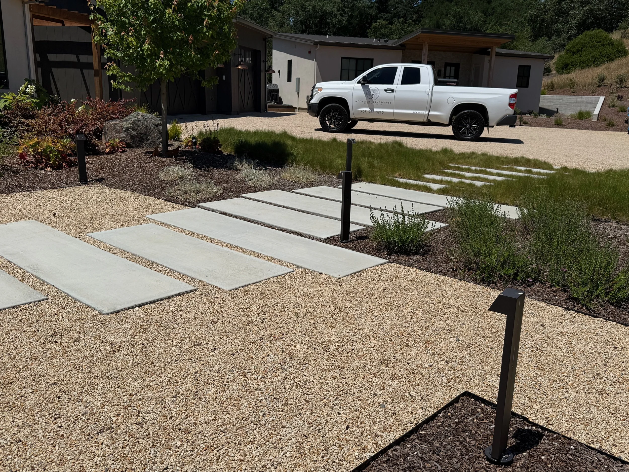 Gravel patio and modern walkway with outdoor pathlights.