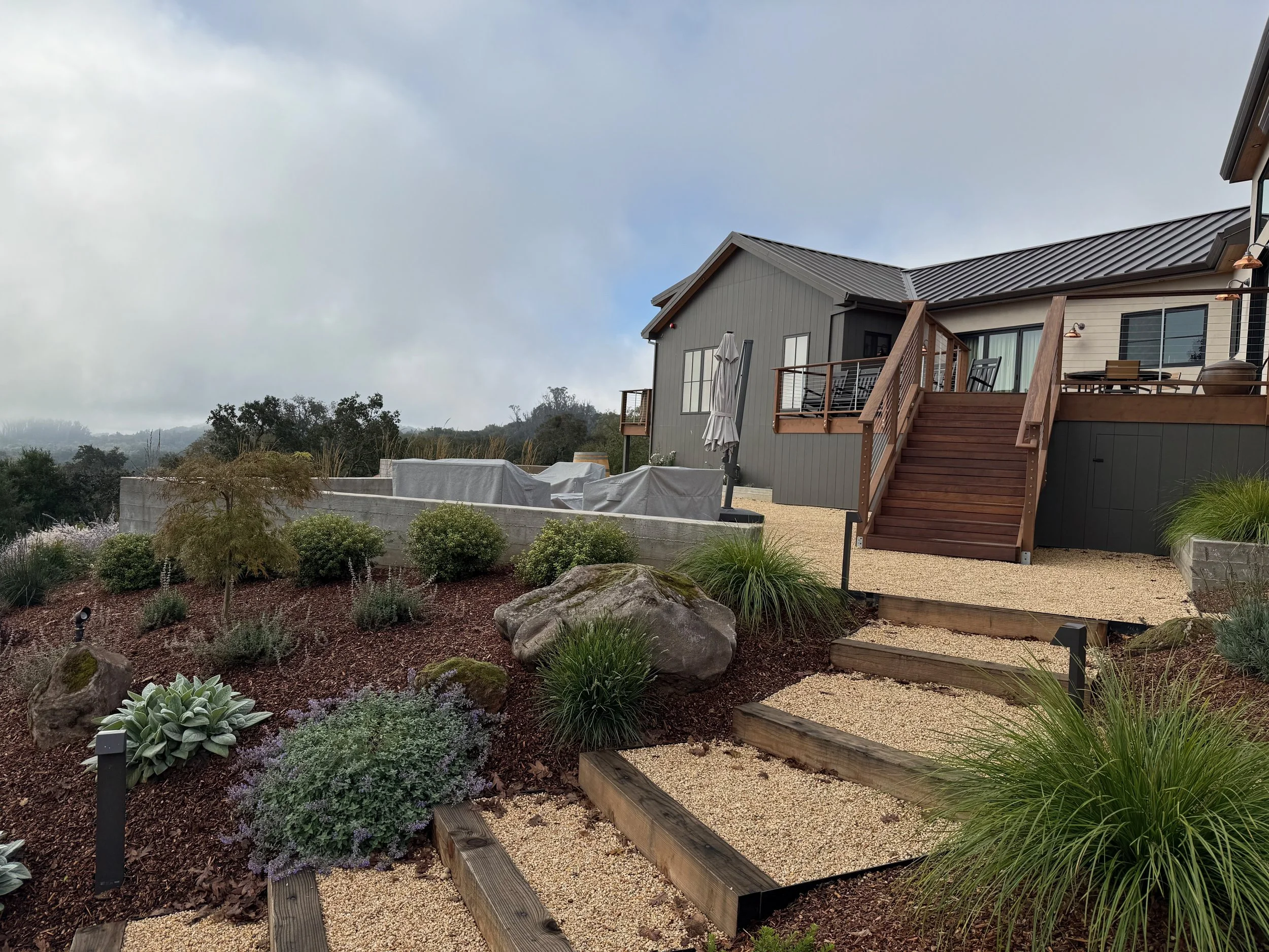 Gravel and wood stairs and surrounding landscaping including deck and Sonoma Fieldstone boulders.