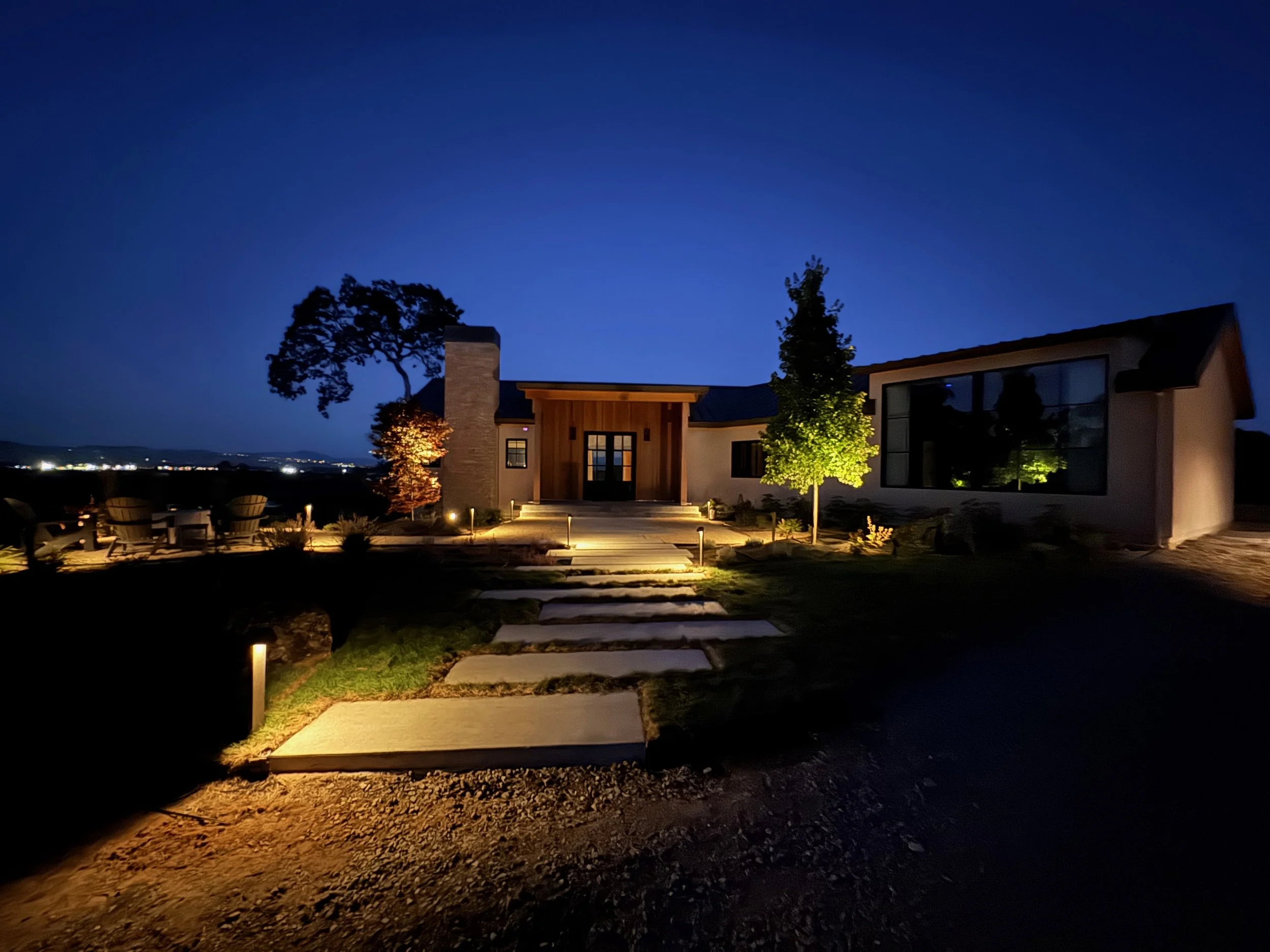 Modern front yard landscape with rectangular concrete steppingstones and outdoor lighting.