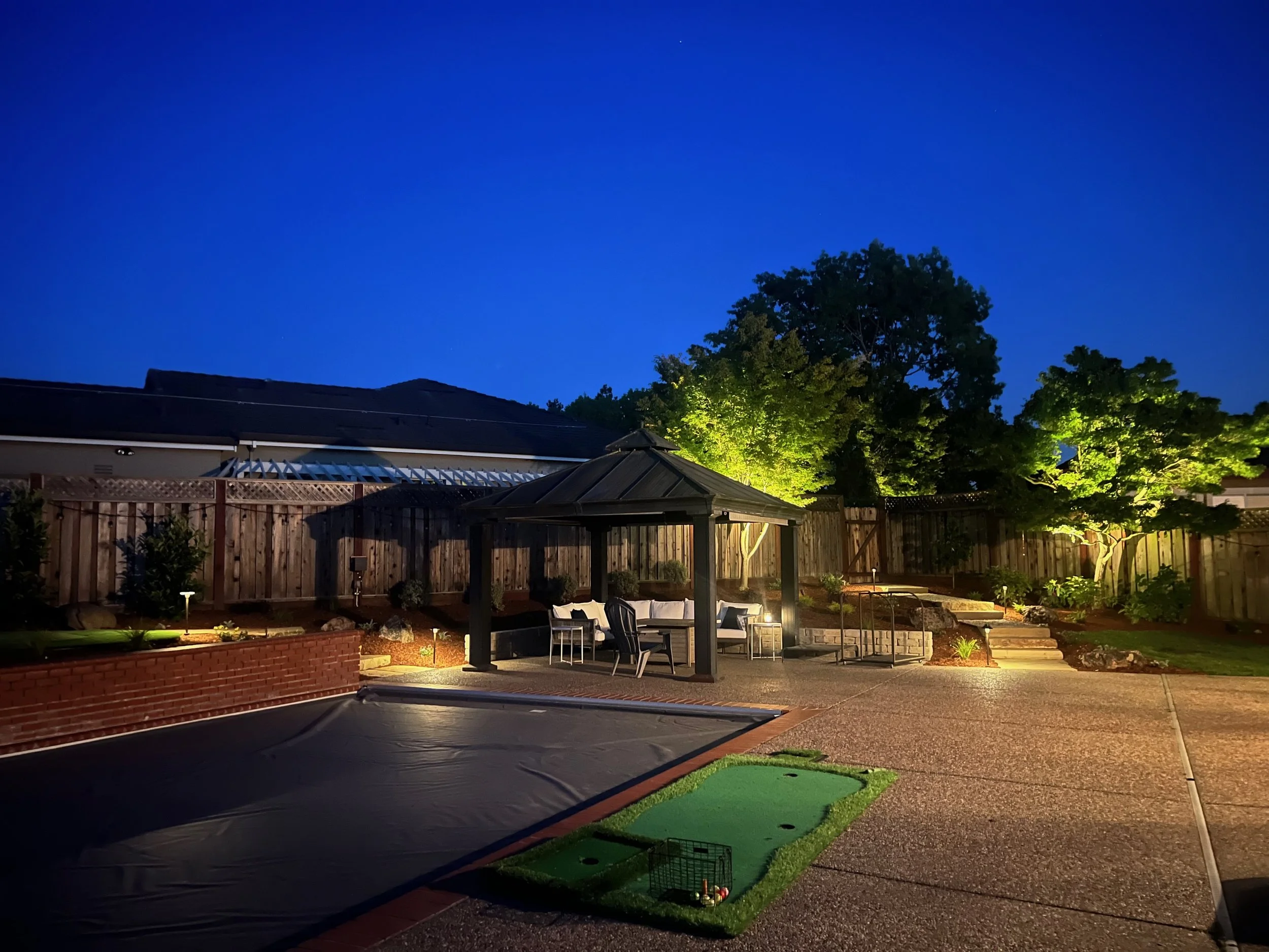 Backyard in Petaluma with pool and surrounding landscape with low voltage lighting.