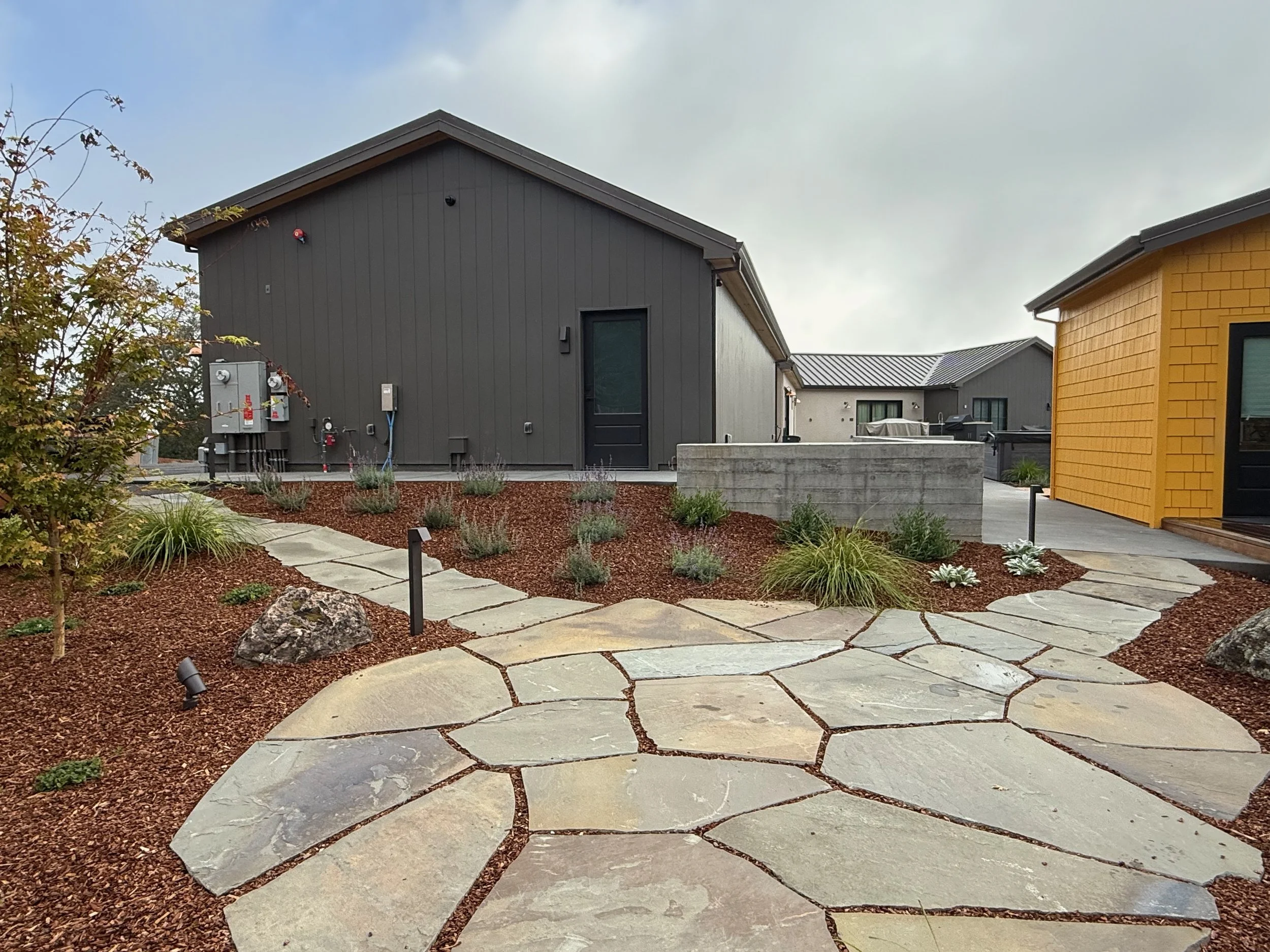 Flagstone patio and two walkways surrounded by modern landscaping and low voltage lighting.