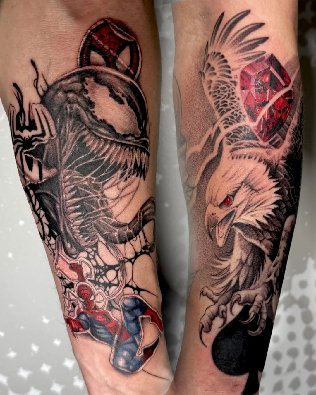 Tattoos of a spider and a spider web on one arm, and a bald eagle with a red ruby eye, a red diamond, and feathers on the other arm.