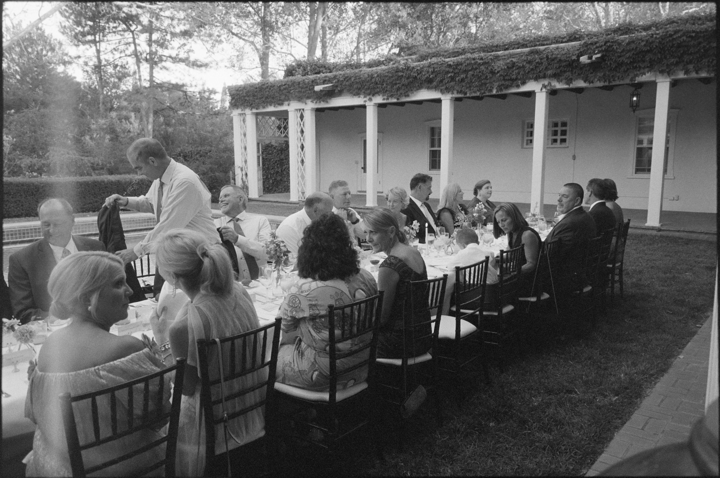 People gathered at a long outdoor table for a meal at Los Poblanos Inn in New Mexico – a boutique hotel.