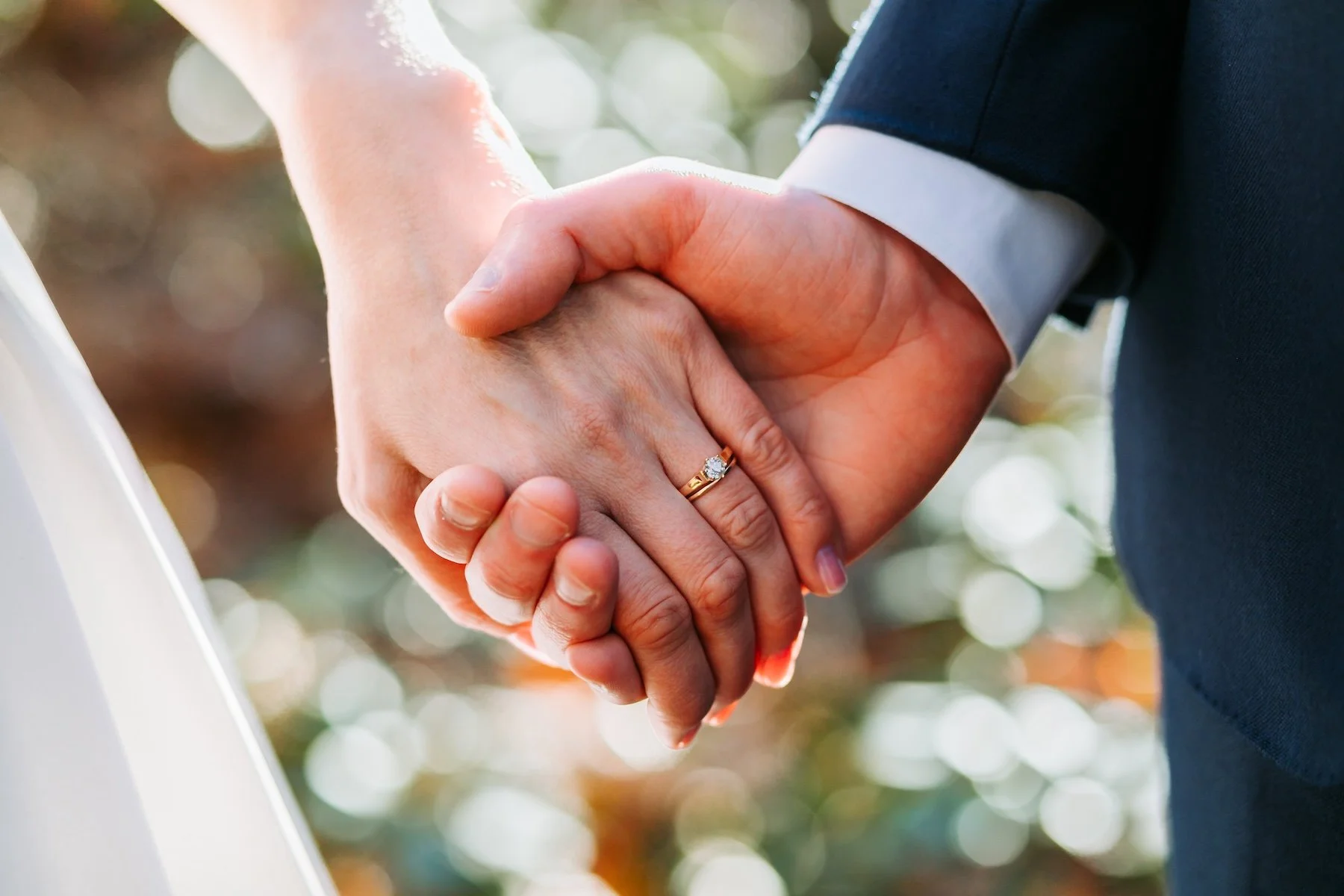 Newlyweds holding hands on a woodland trail covered in fallen autumn leaves during an intimate Massachusetts elopement.