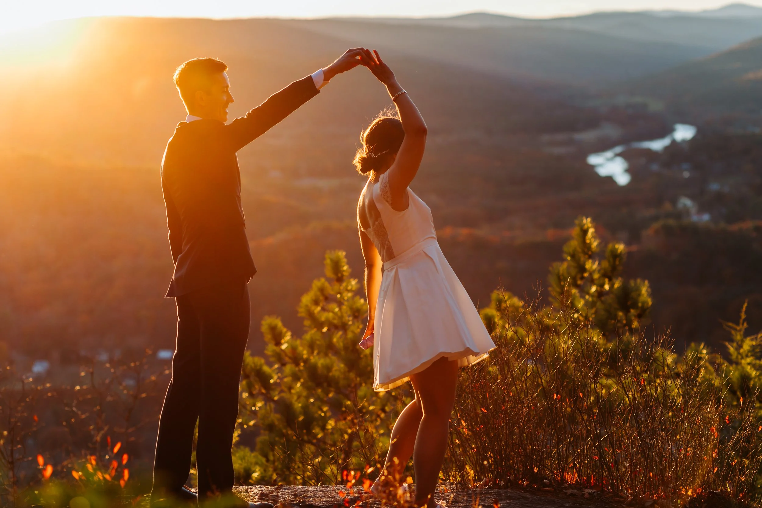 Couple dancing in silhouette at sunset above a New England valley during their fall elopement.