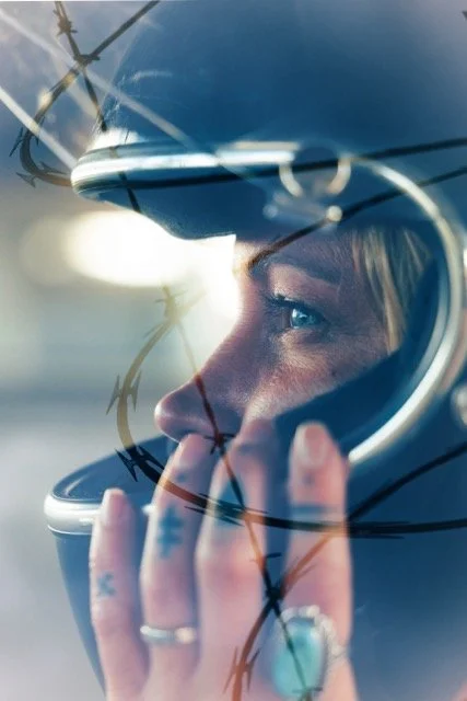 Close-up of a woman wearing a helmet and reflective sunglasses, looking into the distance.