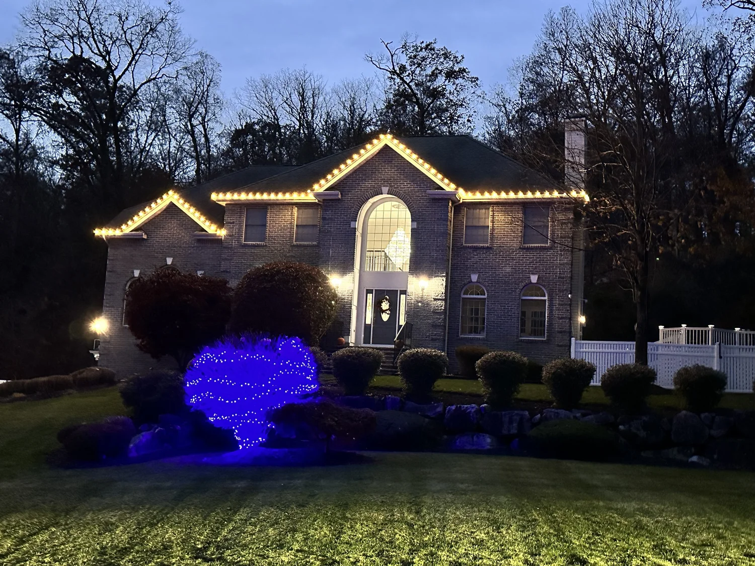 Warm white roofline lighting with a blue-lit landscape