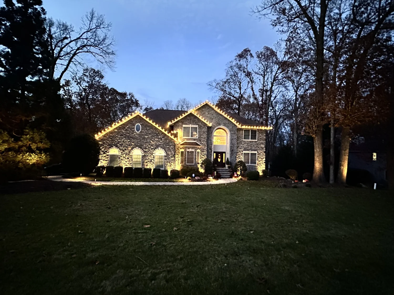 New Jersey home with warm white holiday lights along its rooflines