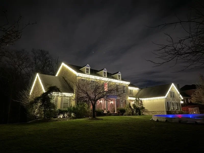 Home outlined in warm white holiday lights at night
