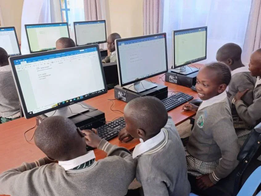 Children sit at computers in a computer lab, working