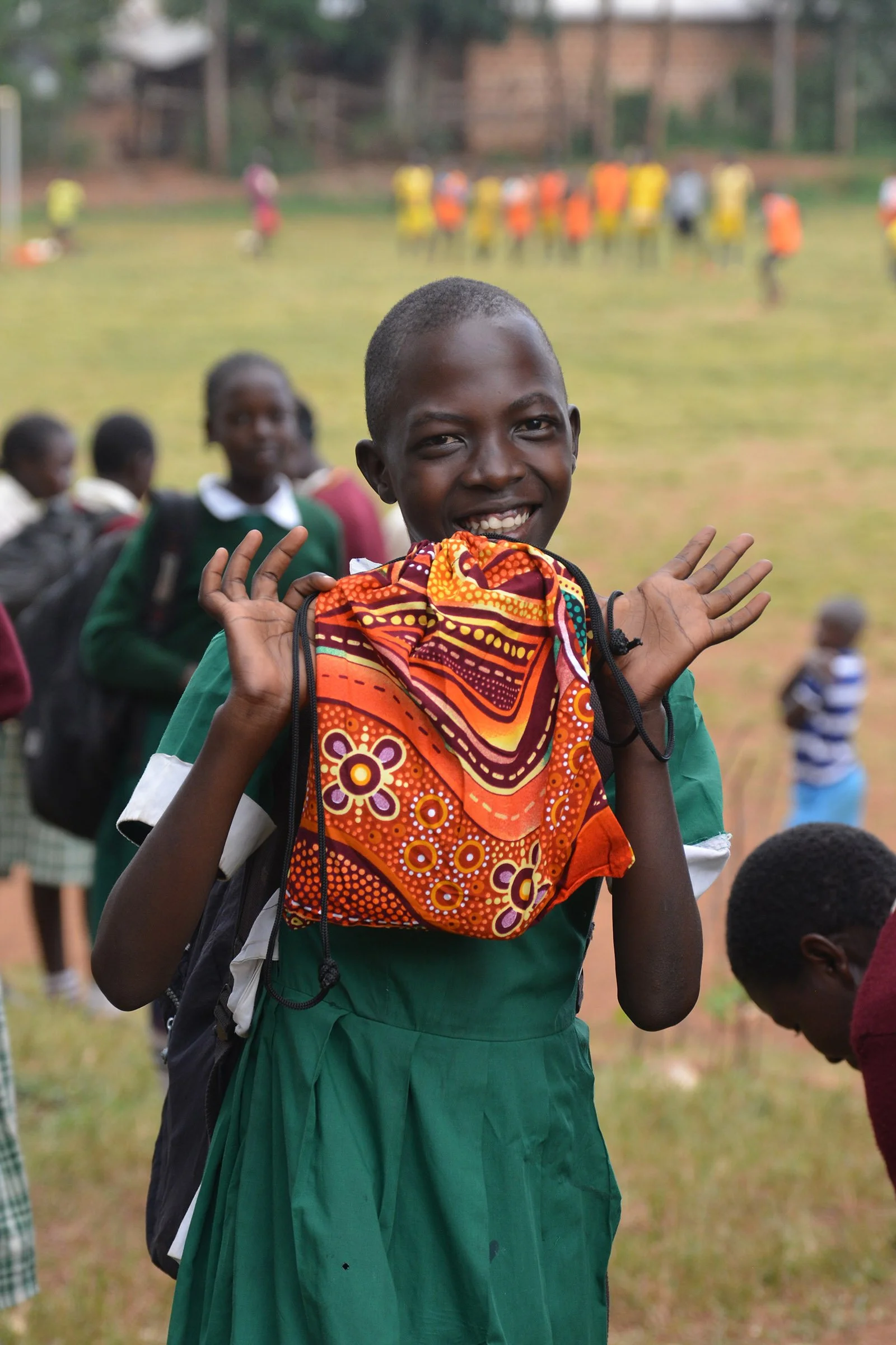 A girl in a green uniform stands, holding her Days for Girls bag