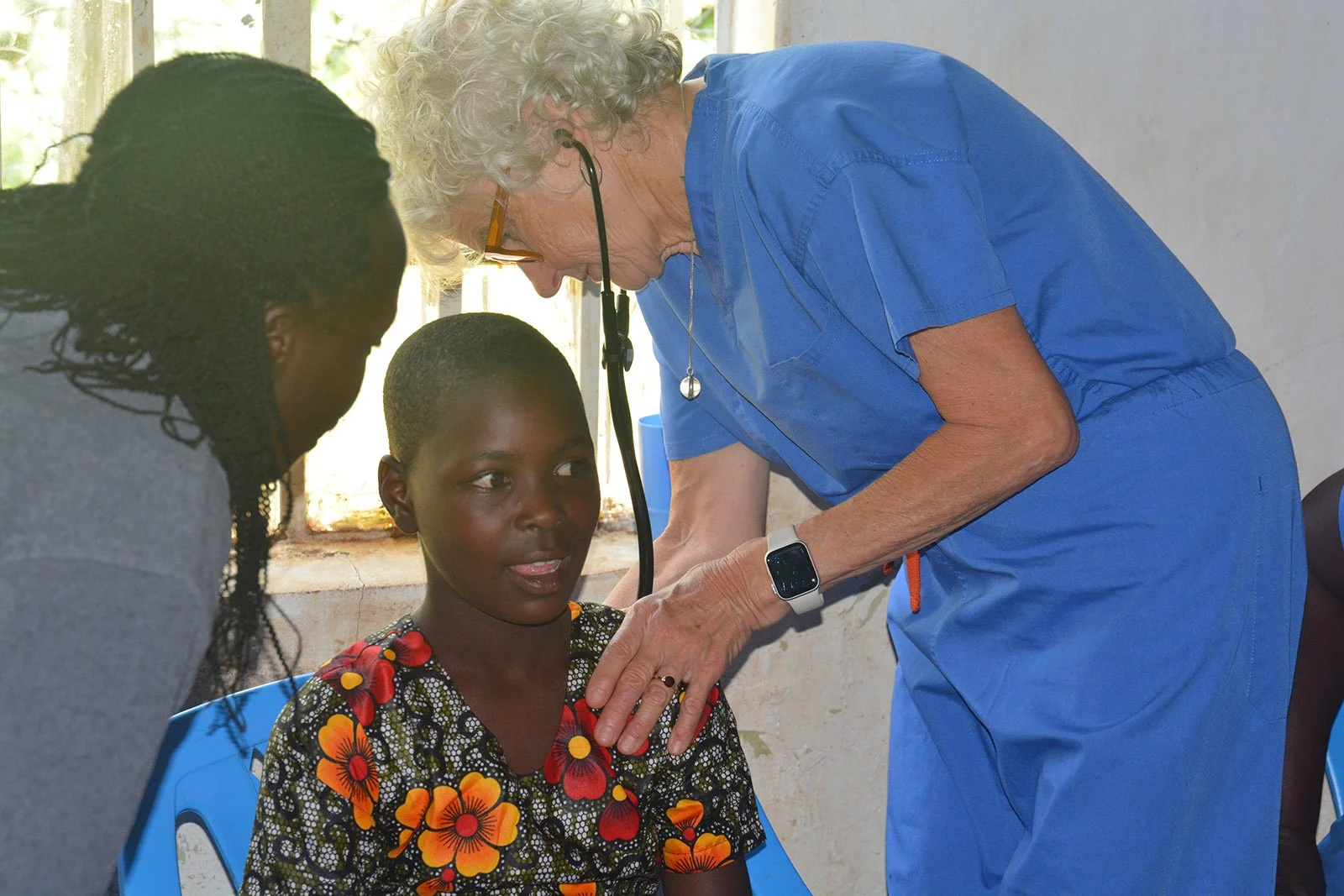 A woman in blue scrubs takes care of a patient at the medical clinic