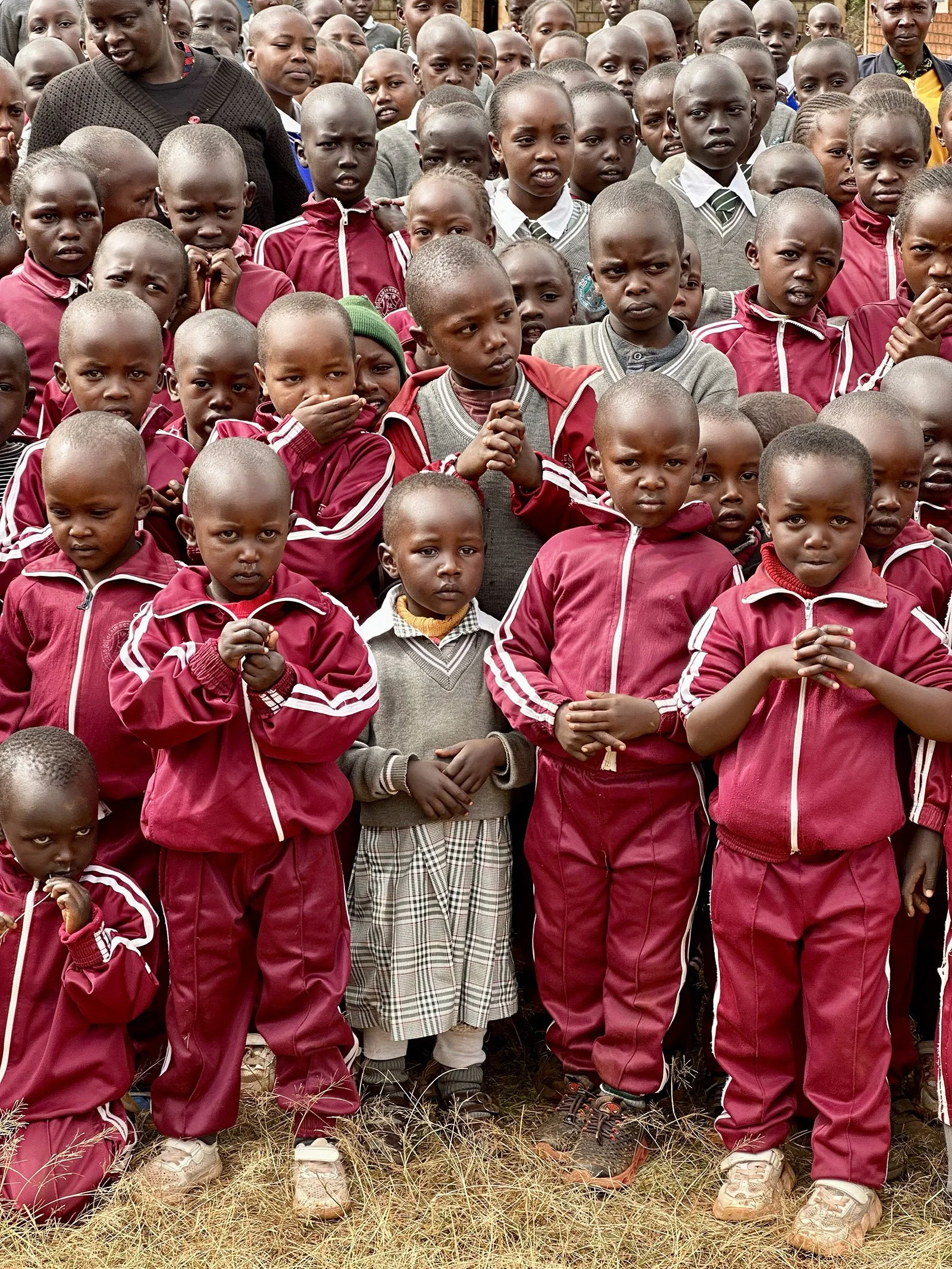 A group of children in red uniforms stand together.