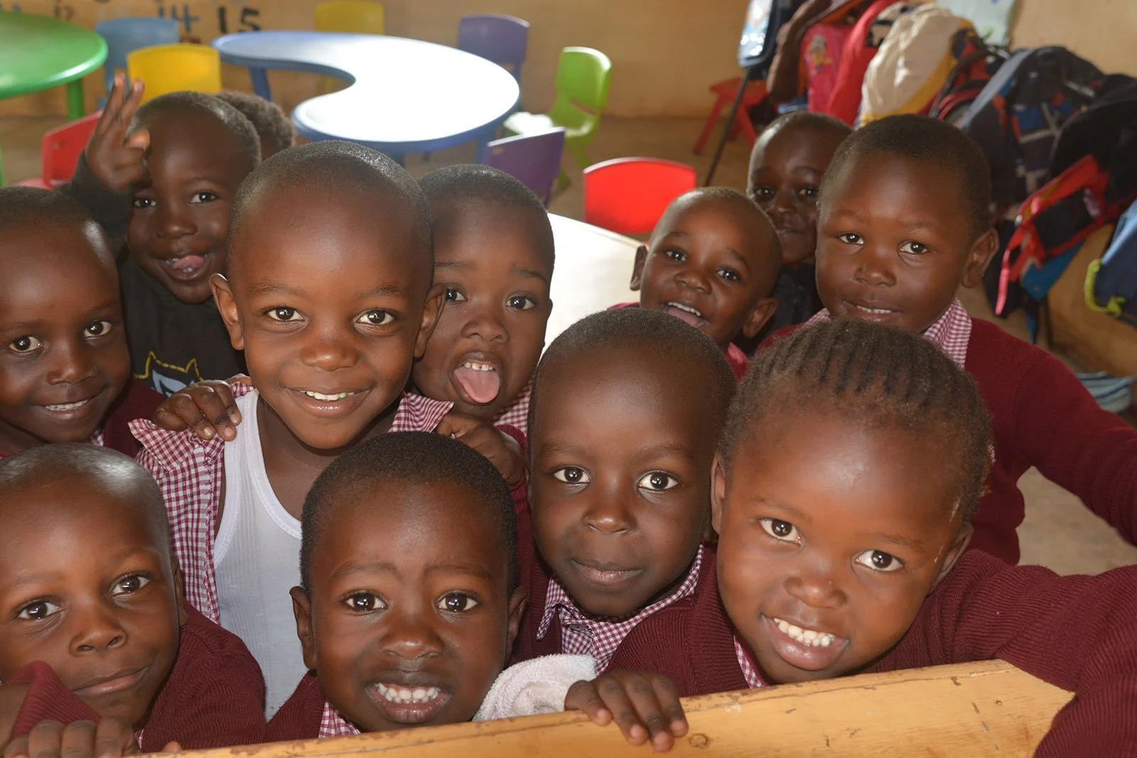 A group of young children in red uniforms stand and smile.