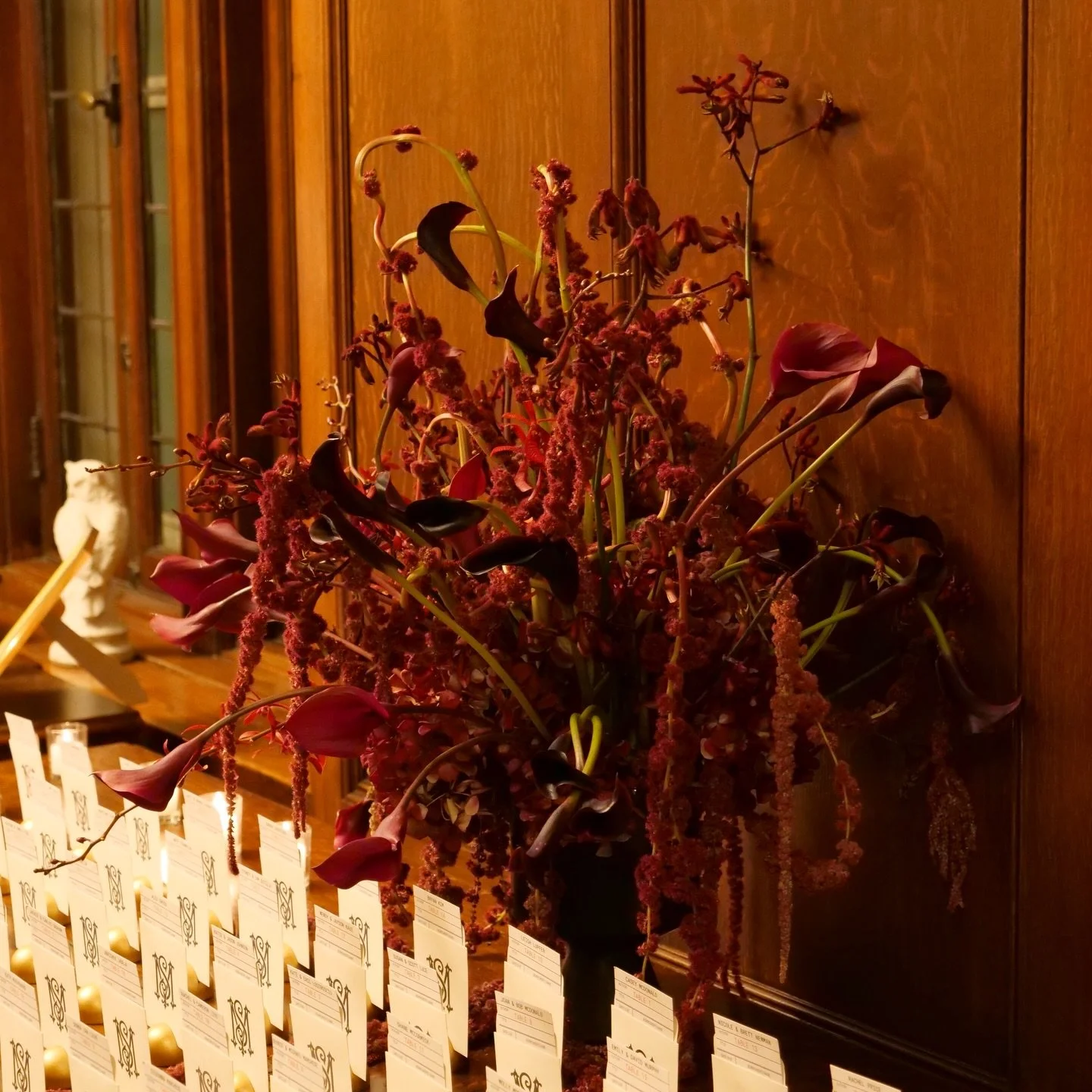 Sculptural. Unexpected. Intentionally undone.

An escort card table reimagined as a living composition; cascading amaranthus, inky calla lilies, playful orchids, and expressive, architectural movement. Each stem placed to intrigue, to invite pause, t