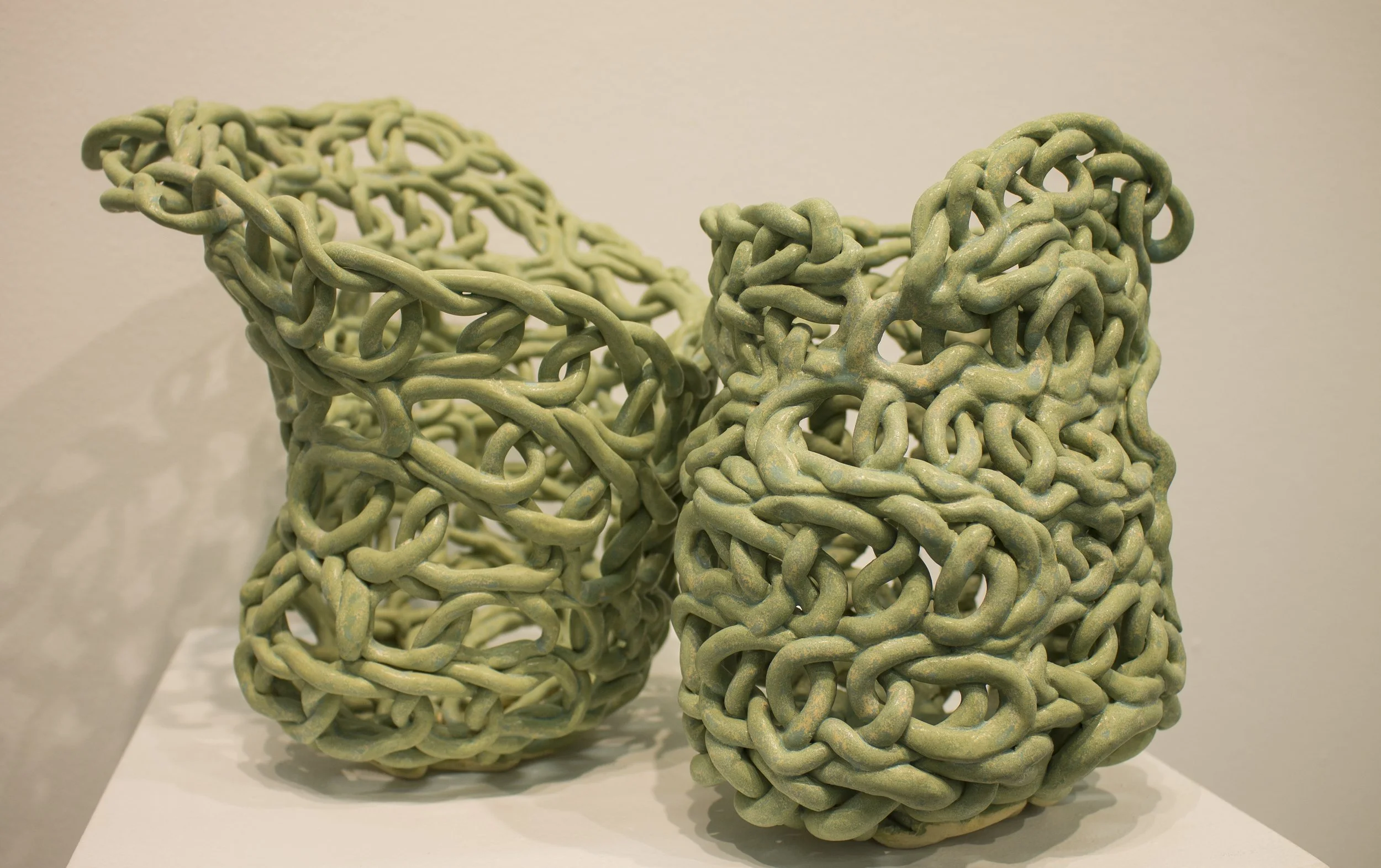 Abrasive Entanglement, 2023, 10in. x 14in. x 6in, Ceramic and unraveled nylon rope.
 
This piece was created by creating opposing movement in two hollow clay forms. The steely finish of the ceramic highlights the creases and indentations. This is con