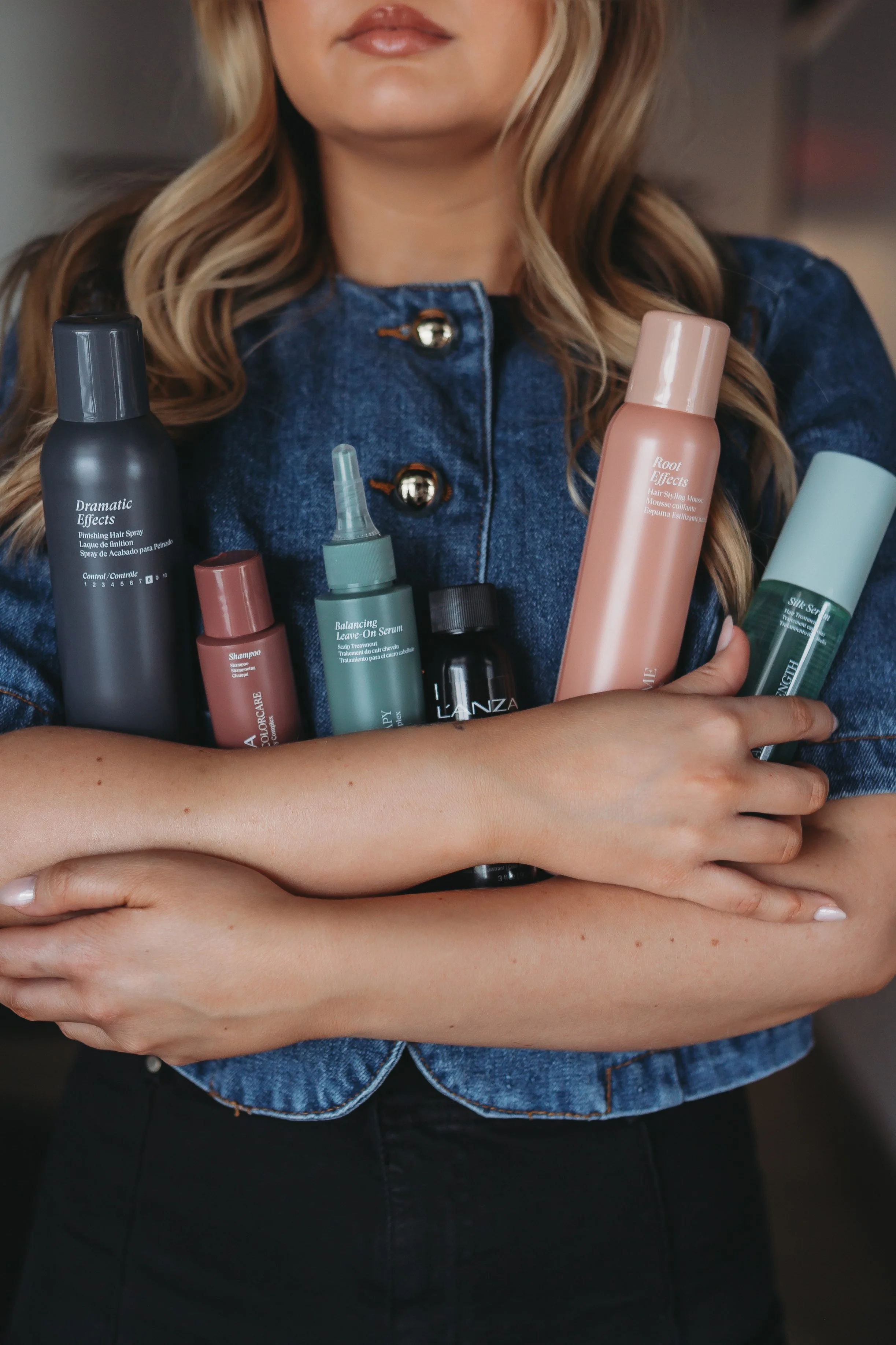 Stylist holding L'ANZA haircare products at Grand Noir Salon in Verona, WI