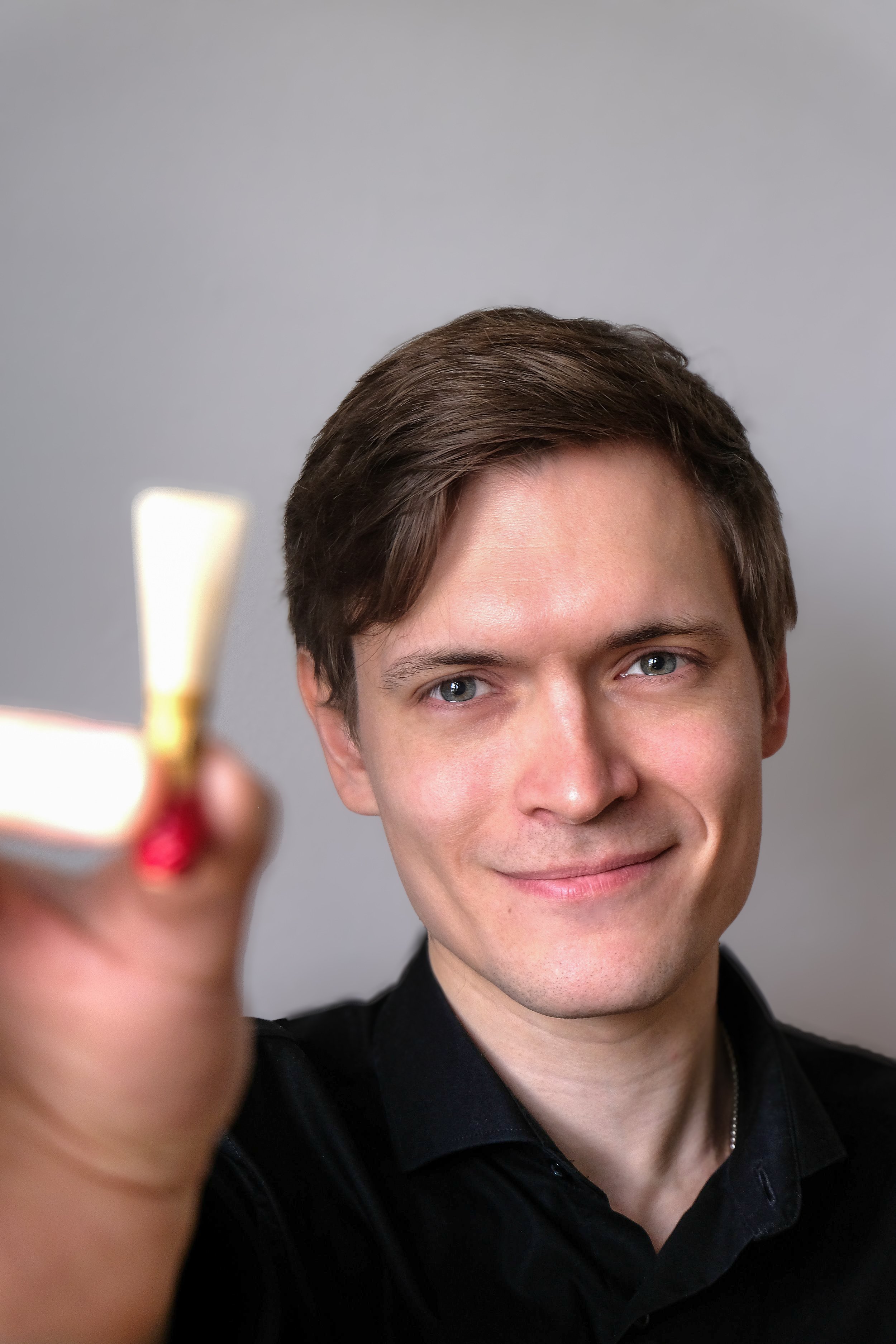 Junger Mann mit braunen Haaren und blauen Augen hält ein Fagottrohr vor der Kamera.