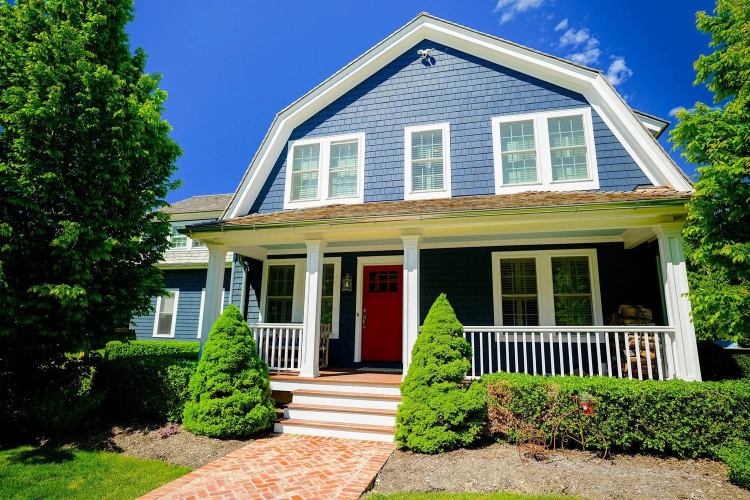 Front view of a blue shingle-sided home with white trim and a covered porch