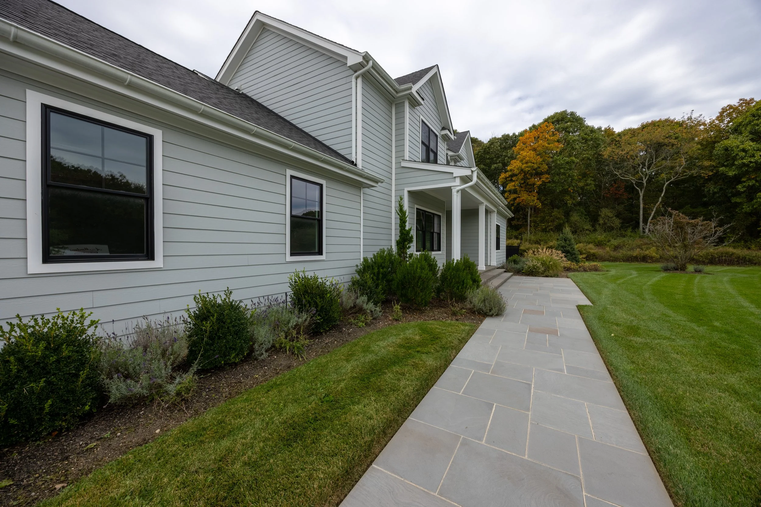 Light gray lap siding with white trim, black windows and landscaped walkway by C. Staker Remodeling