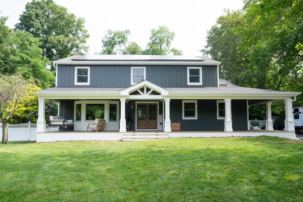 Front view of a dark gray home with white siding trim and a covered porch