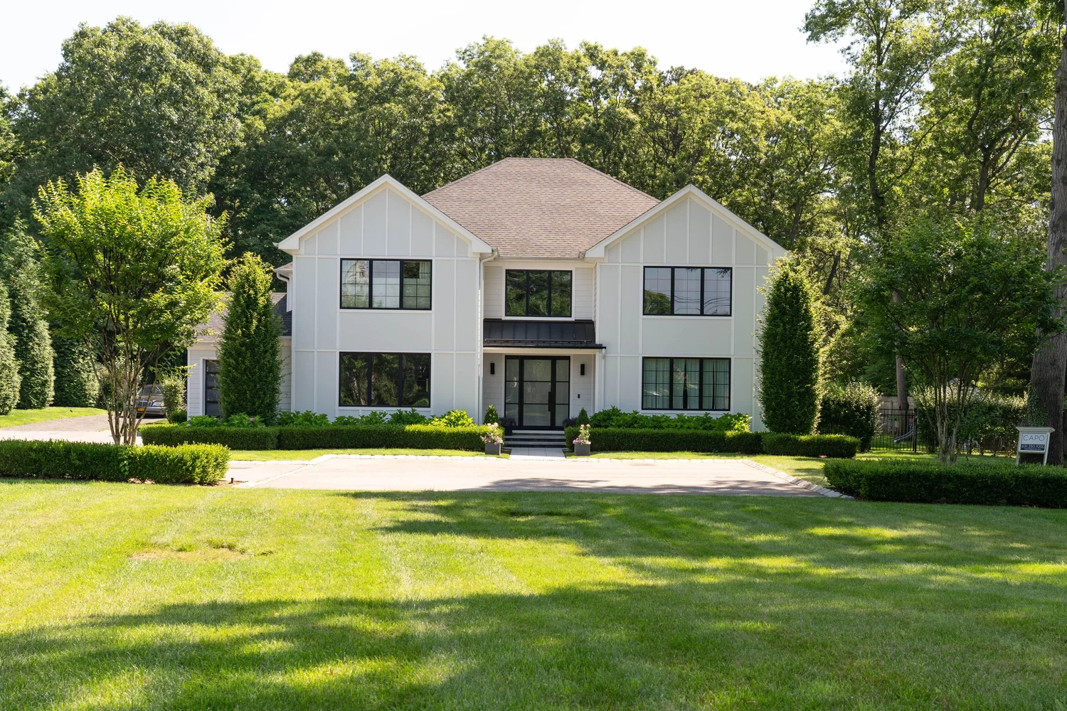 Front view of a white home with board-and-batten siding and black-framed windows