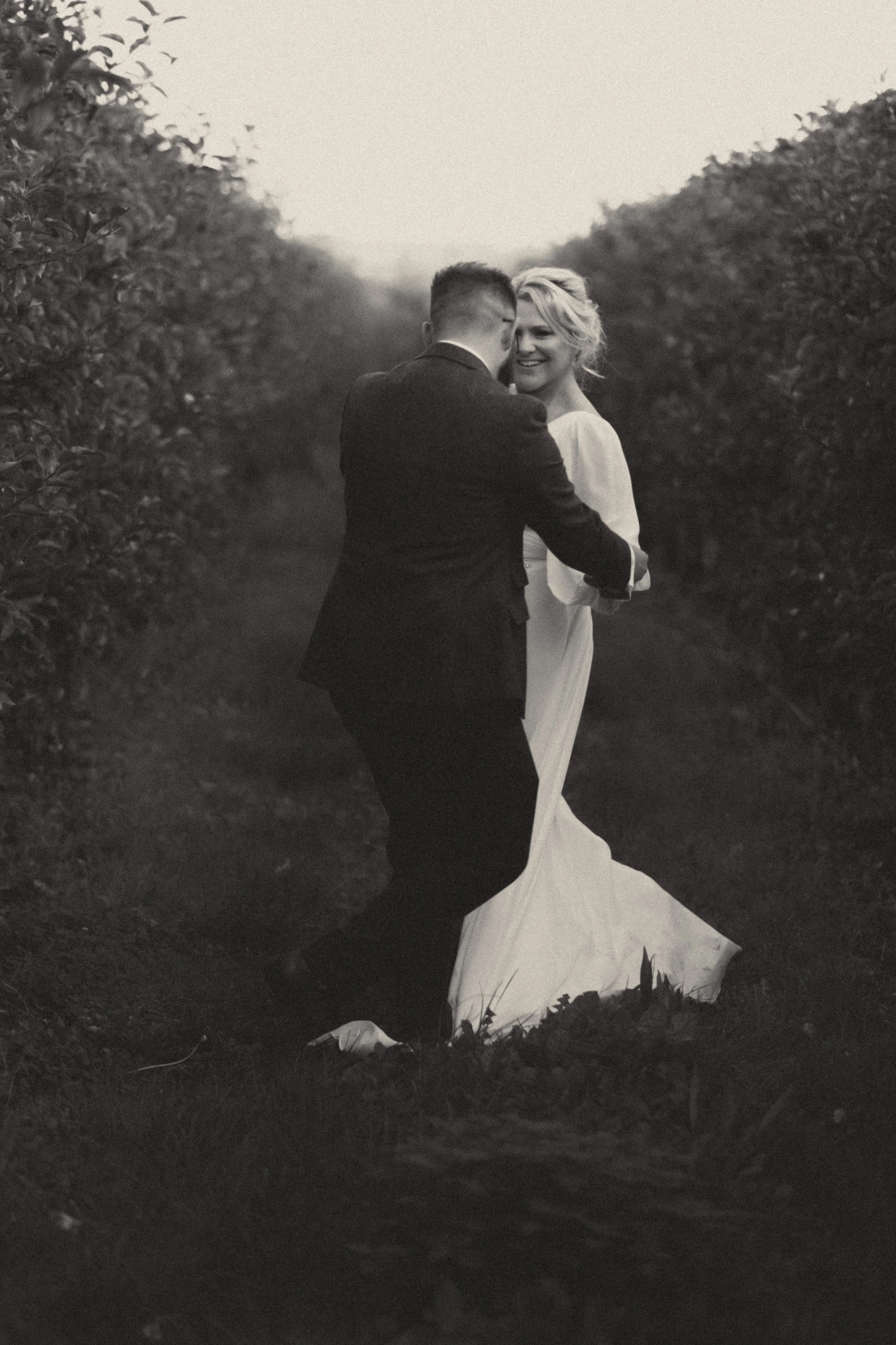 Natural, Black and white, romantic Wedding photography moment, capturing a bride and groom dancing outdoors in apple orchard at Glewstone Court, Ross on Wye