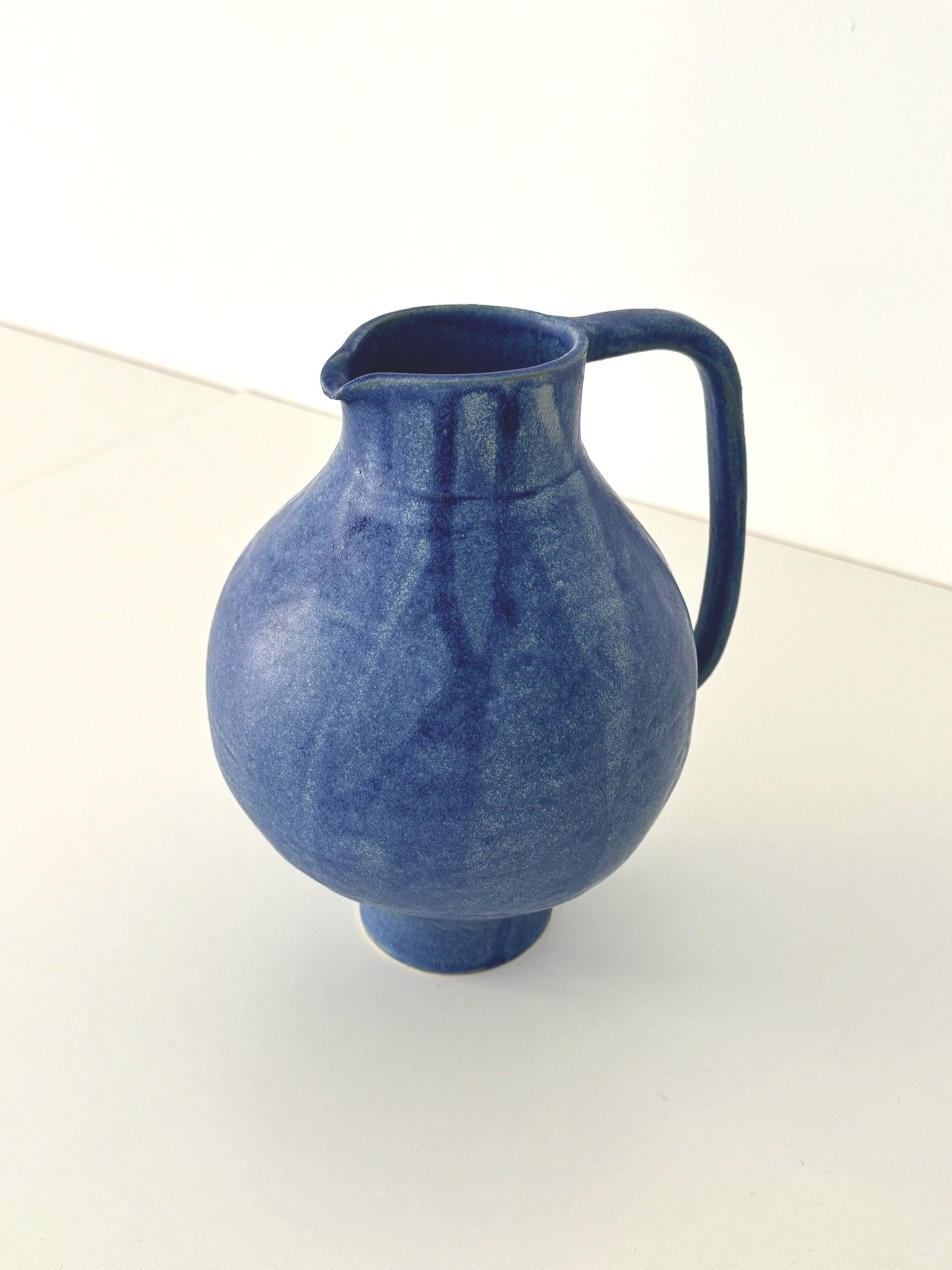 Blaue Keramikvase mit Henkel auf weißem Hintergrund